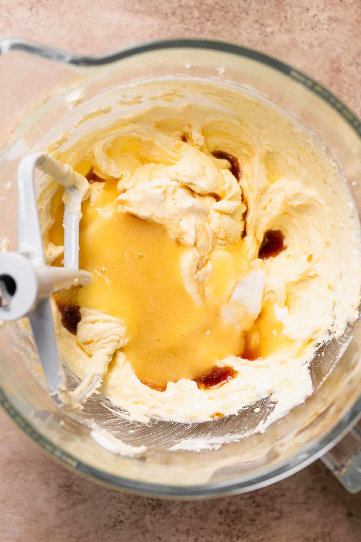 A mixing bowl with the lemon puree, sour cream, and vanilla being mixed into the creamed butter and sugar.