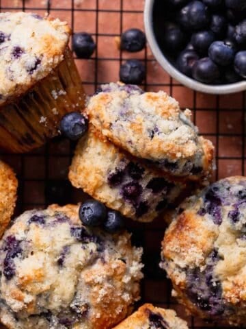 Bakery style blueberry muffins on a wire cooling rack.