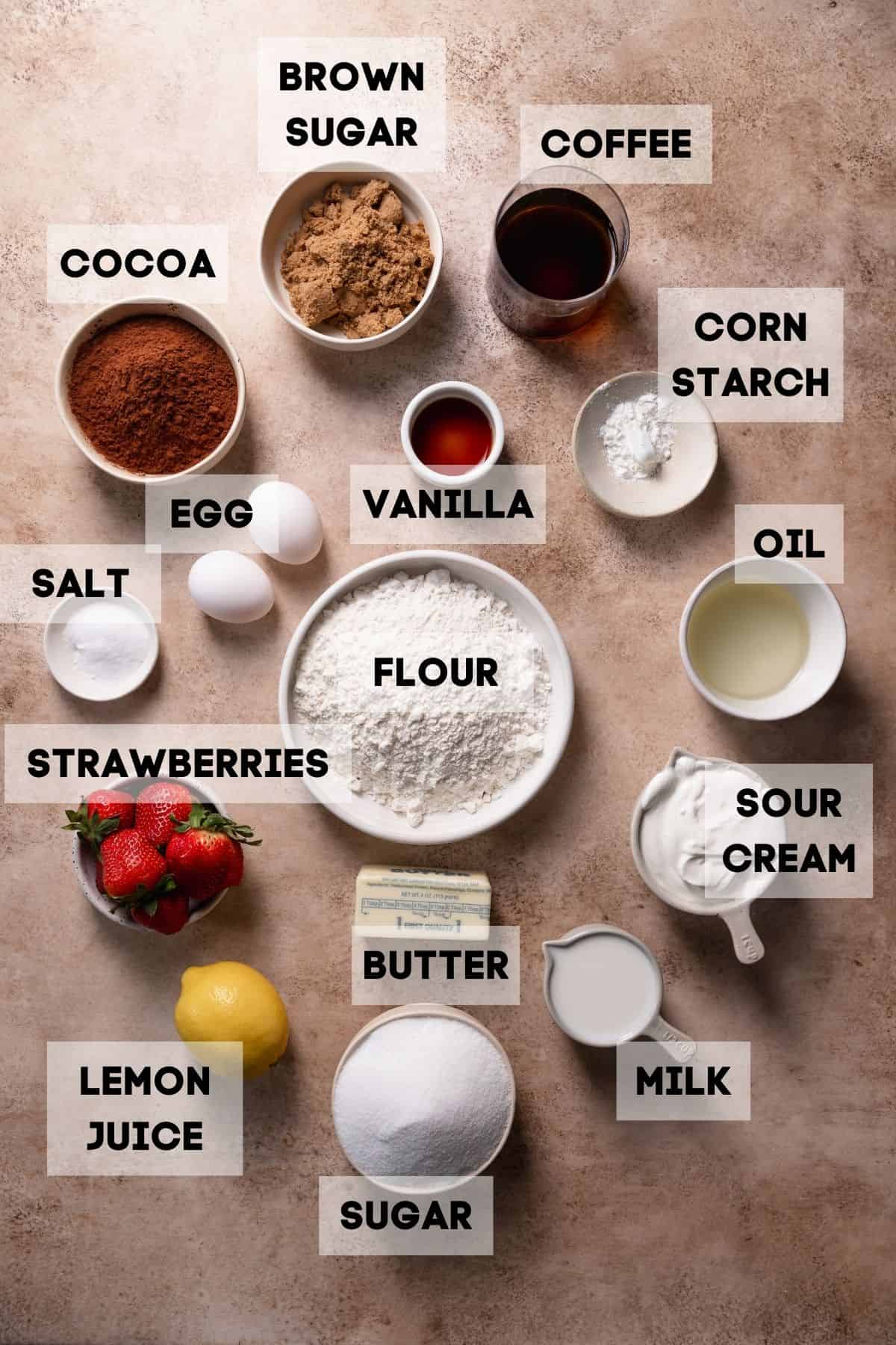 Ingredients needed to make strawberry chocolate cake in bowls with labels.