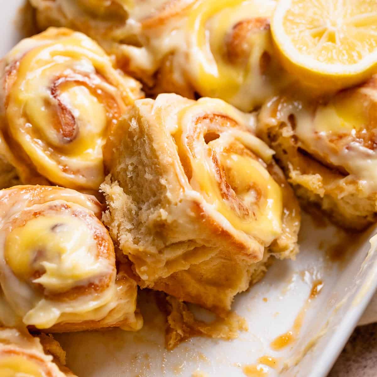 Lemon cinnamon rolls with lemon curd in a white baking dish.