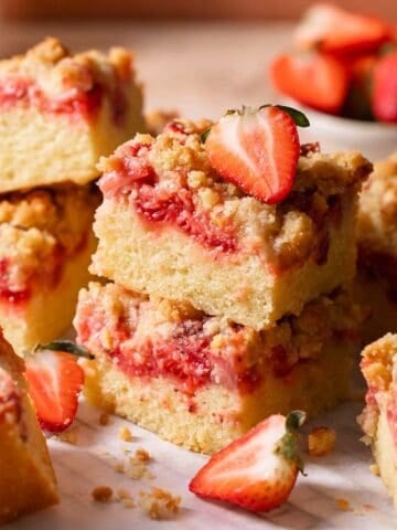 Slices of strawberry crumb cake with fresh strawberries on top on a wire rack.