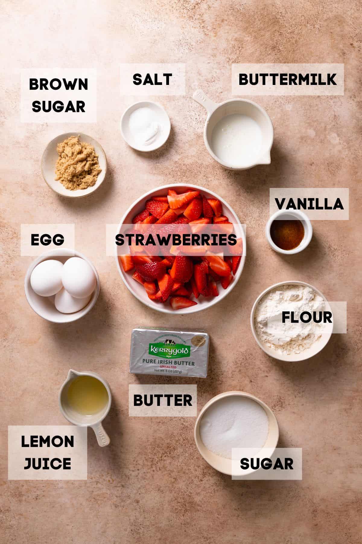 Ingredients needed to make strawberry crumble cake in bowls with labels.