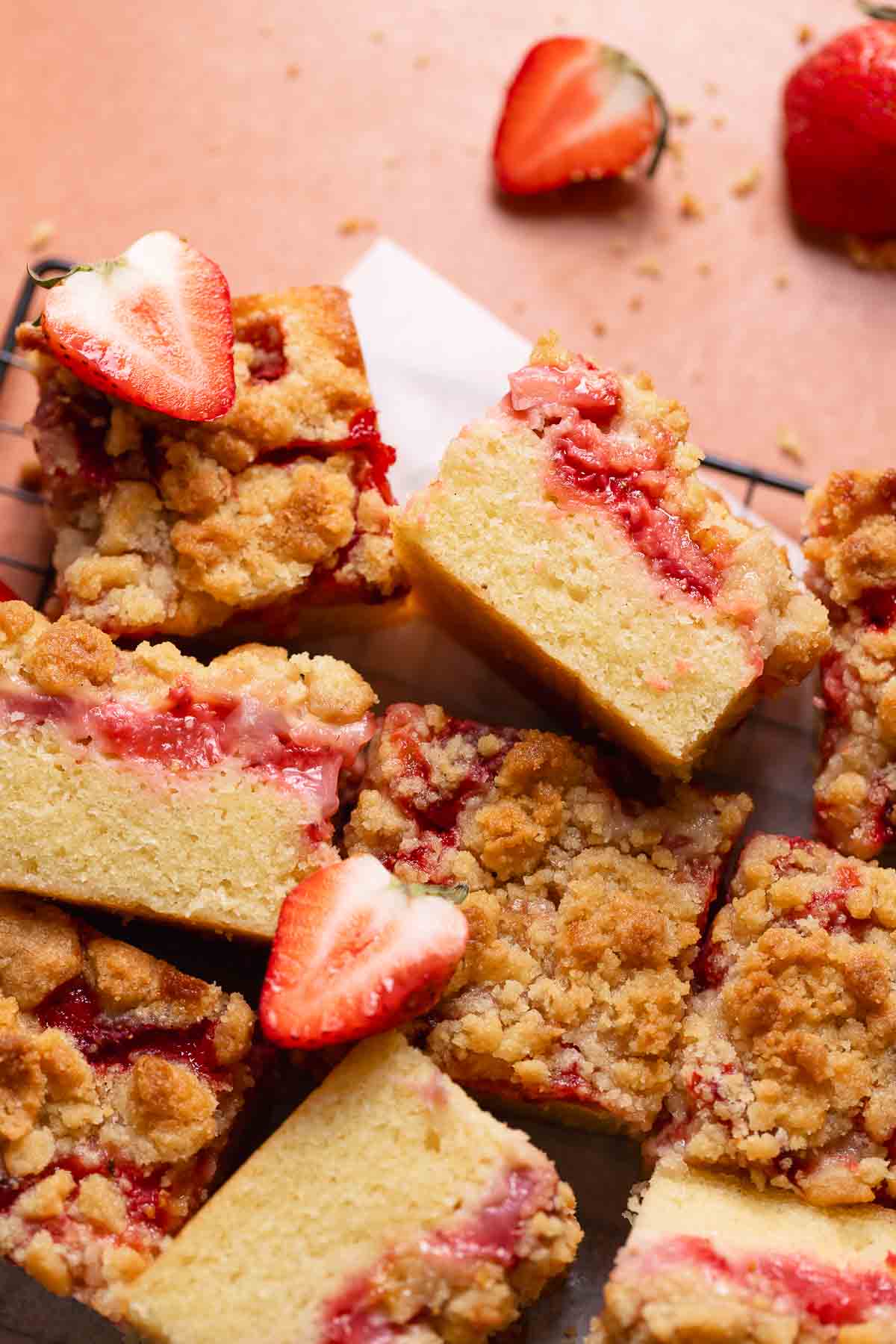 Strawberry coffee cake slices on a wire rack with fresh strawberries on top.