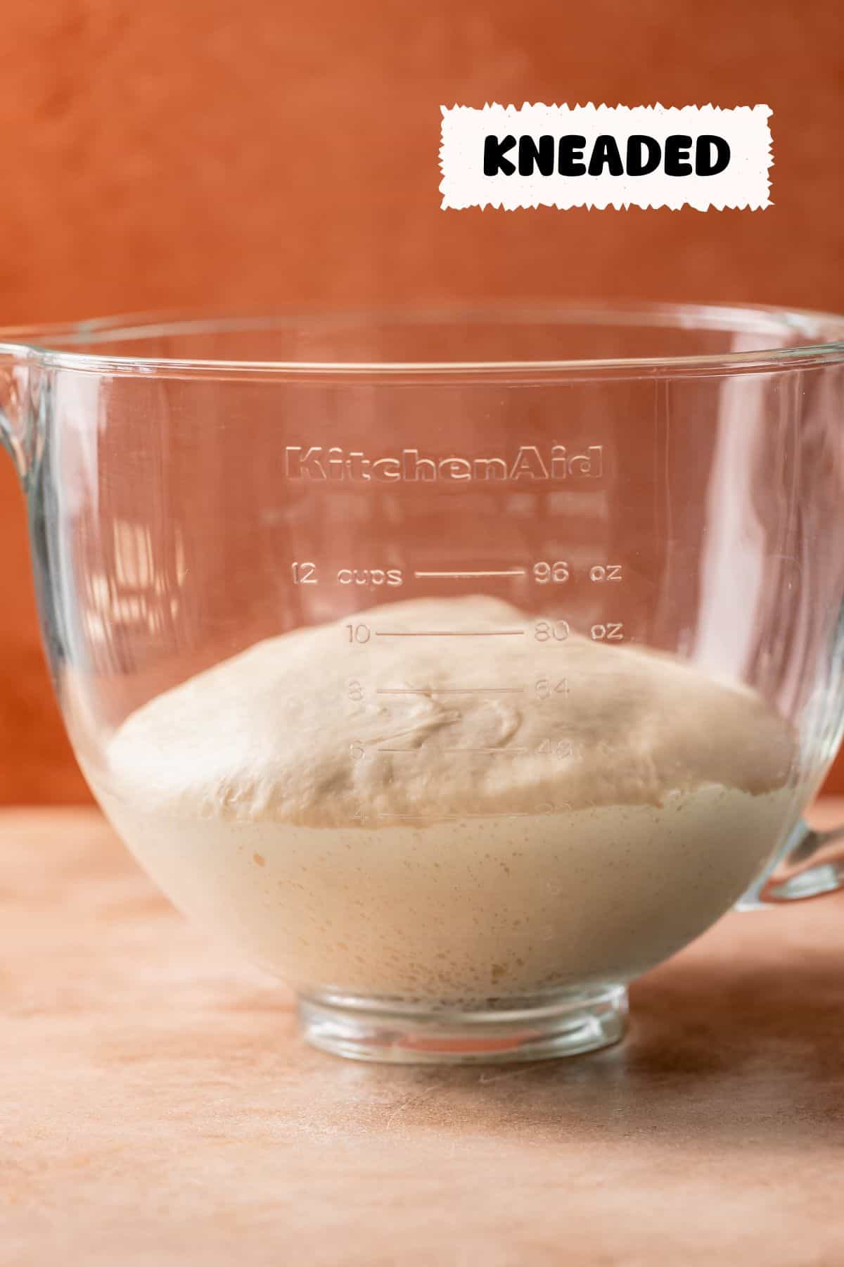 A glass mixing bowl with the kneaded dough after it has risen.