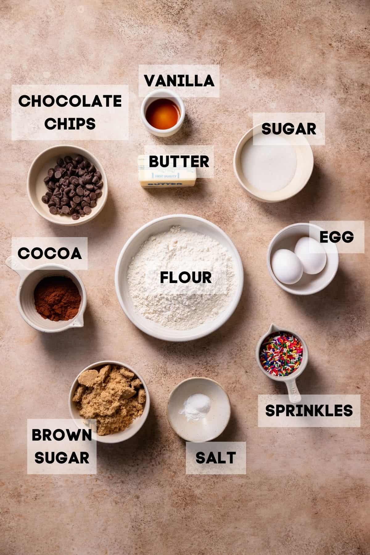 Ingredients needed to make brownies with sprinkles in bowls with labels.