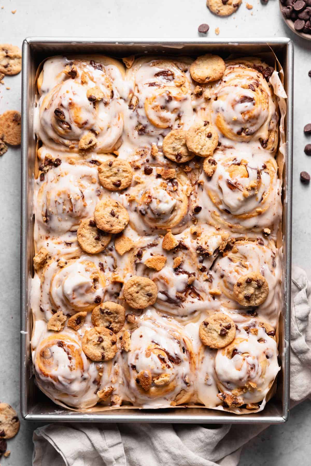 Chocolate chip cookie rolls with vanilla icing and mini cookies on top.