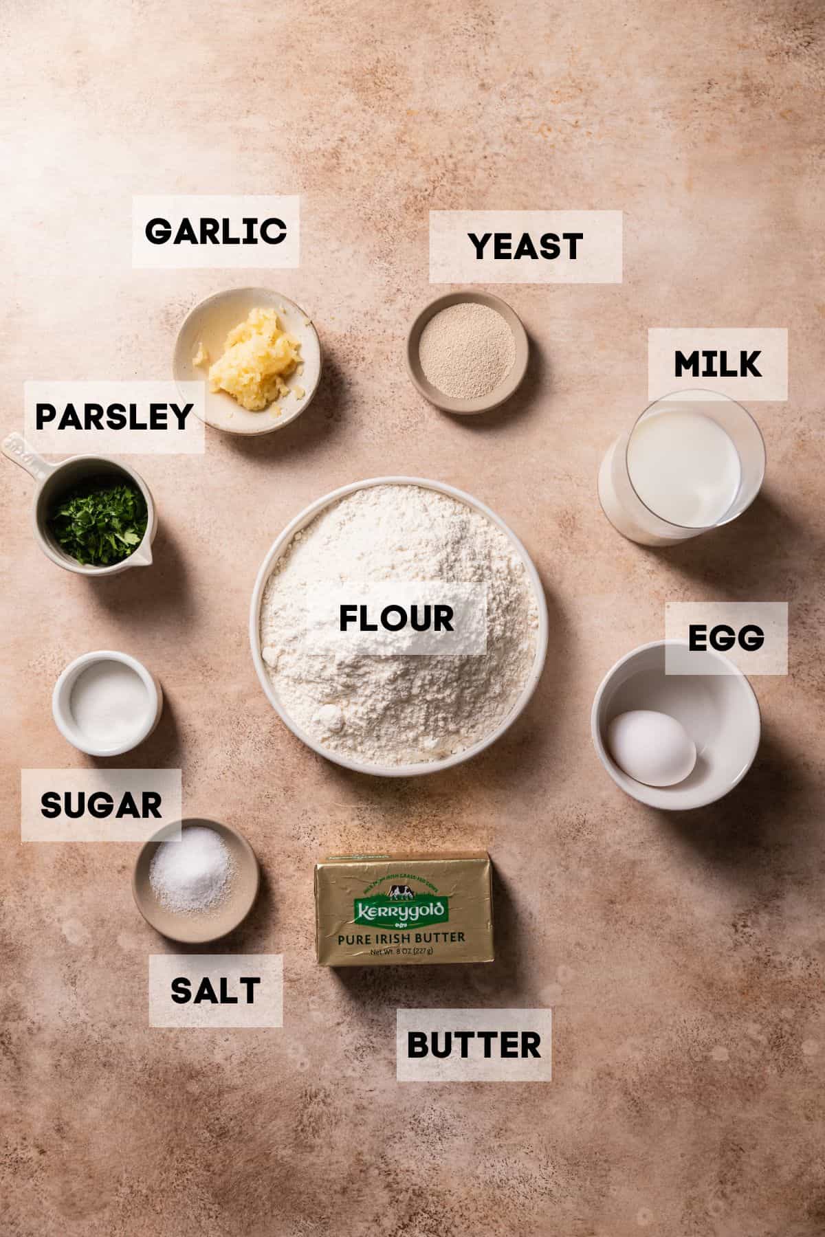 Ingredients needed to make garlic bread rolls in bowls with labels.