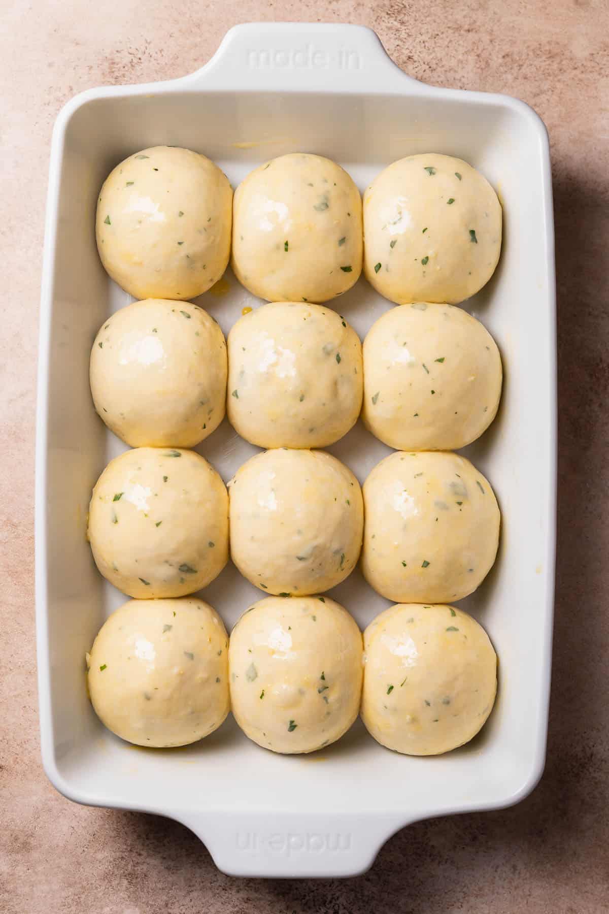 The garlic rolls in a baking pan brushed with egg wash before baking.