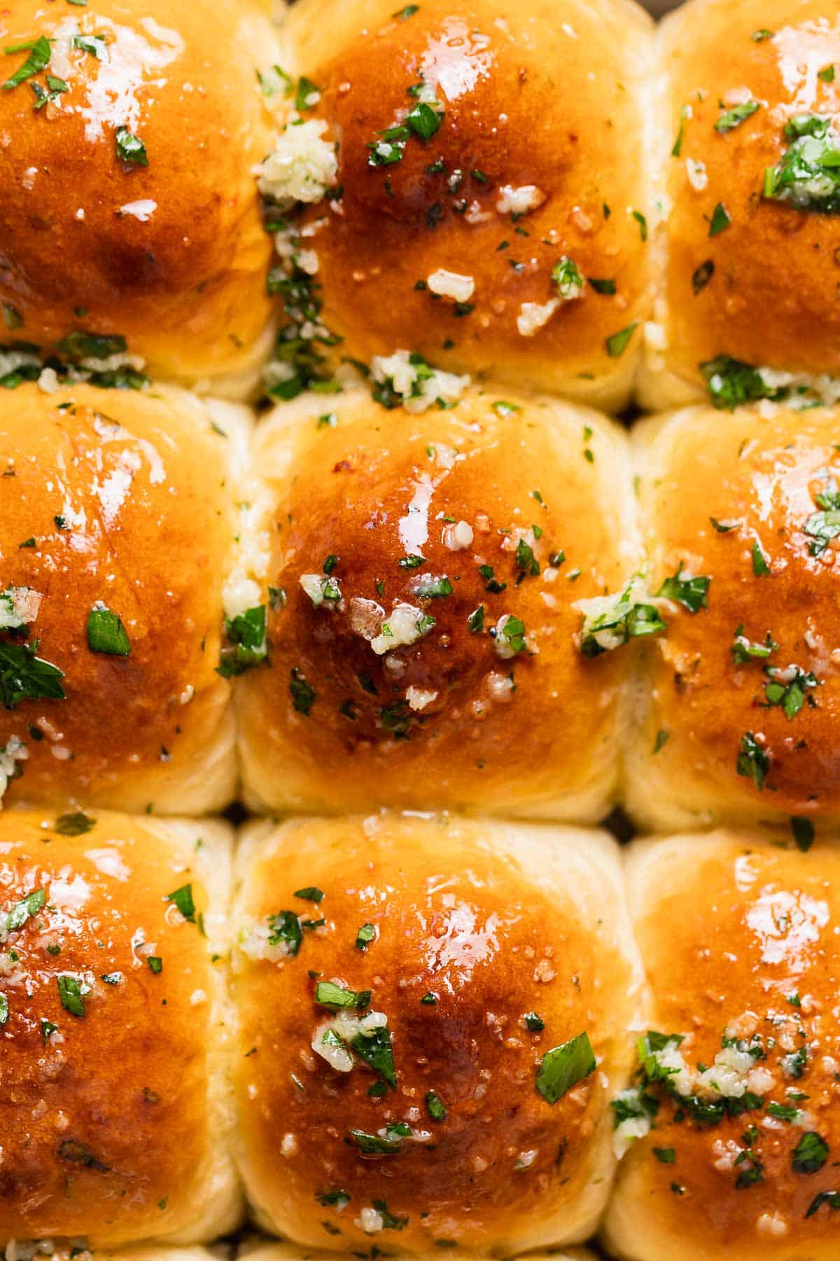 Buttered garlic bread rolls covered in herbs and garlic.