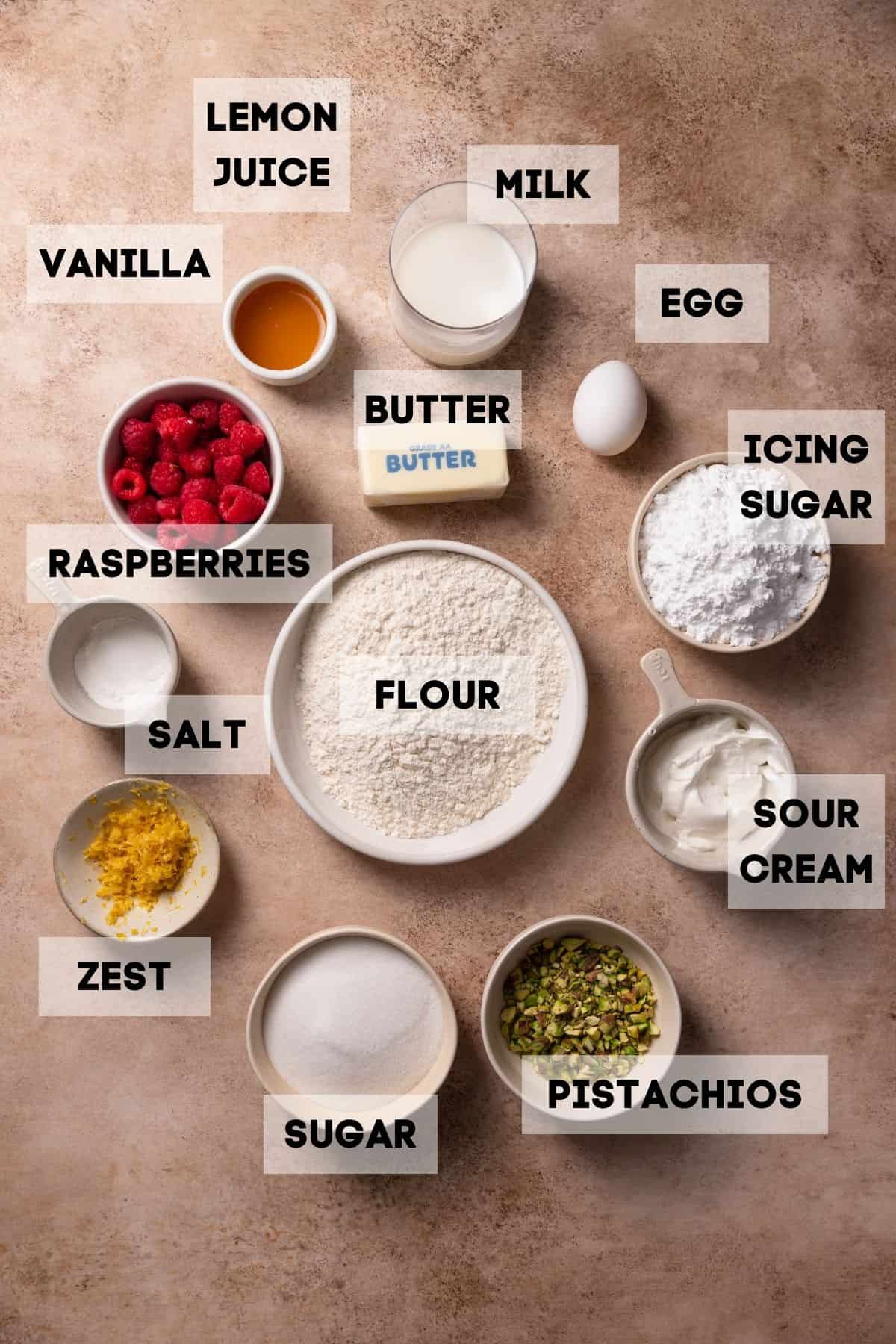 Ingredients needed to make lemon raspberry cupcakes in bowls with labels.