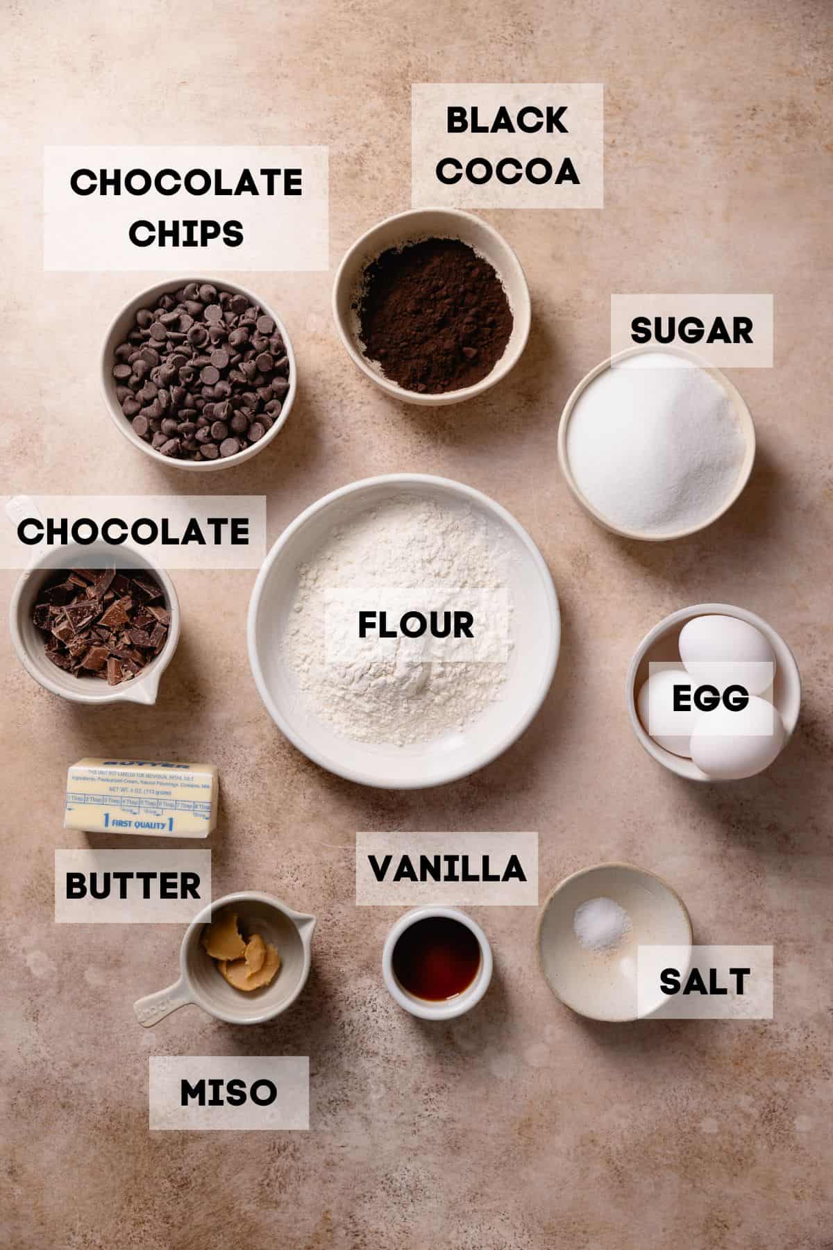 Ingredients to make black cocoa brownies in bowls with labels.