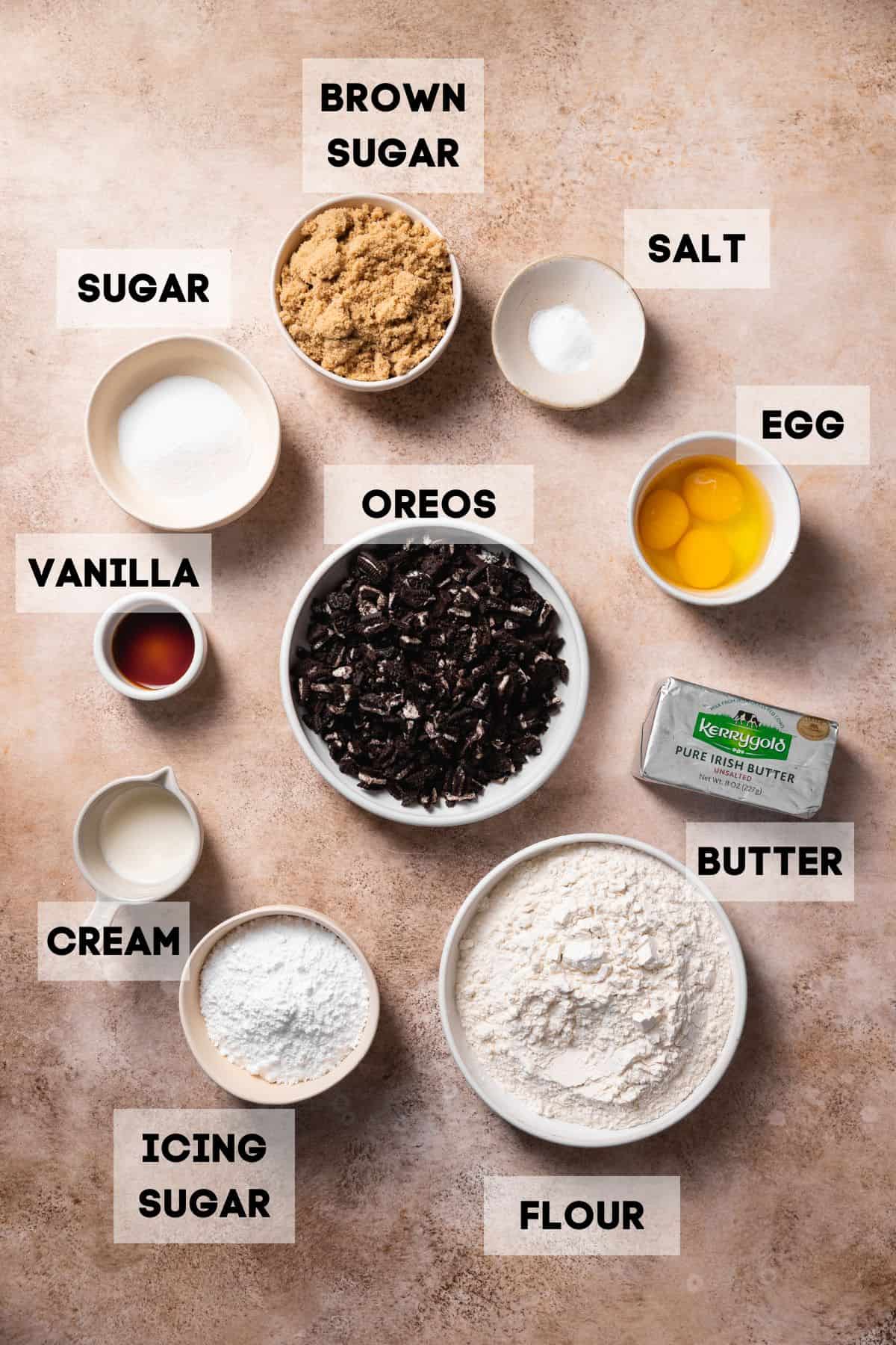 Ingredients needed to make oreo cake in bowls with labels.