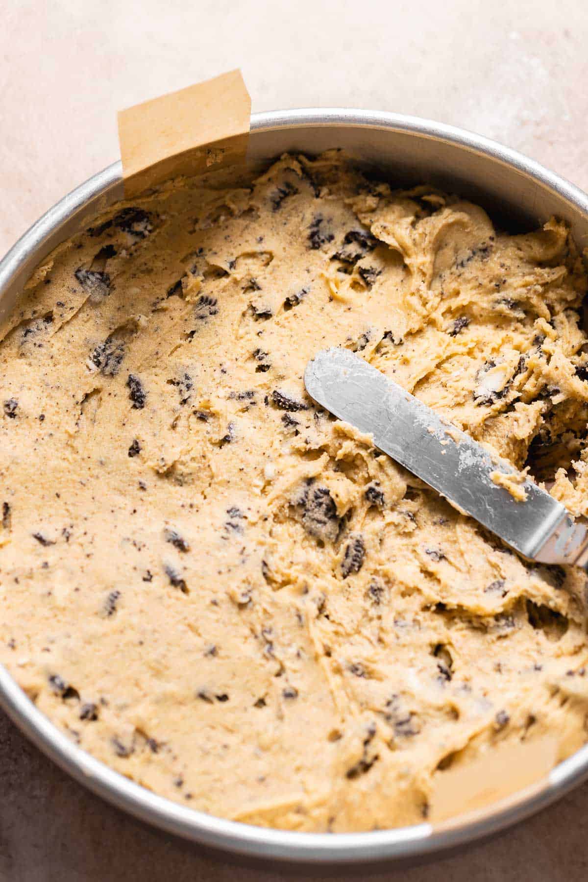 A spatula spreading the oreo cookie dough into the cake pan.