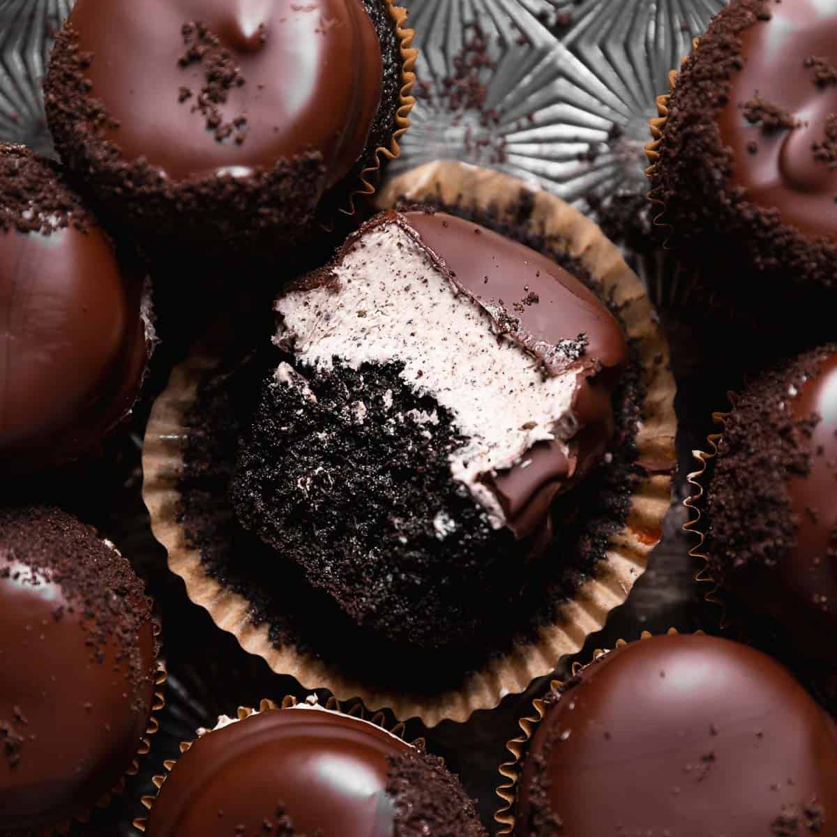 Chocolate oreo cupcake with a bite missing on a black baking tray.