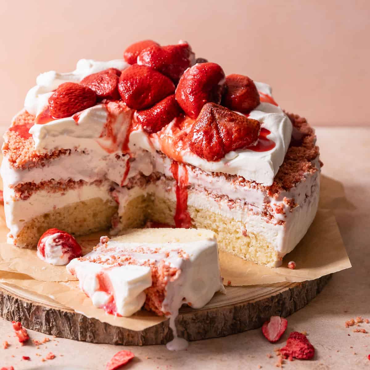 Strawberry shortcake ice cream cake on a wooden cake stand.