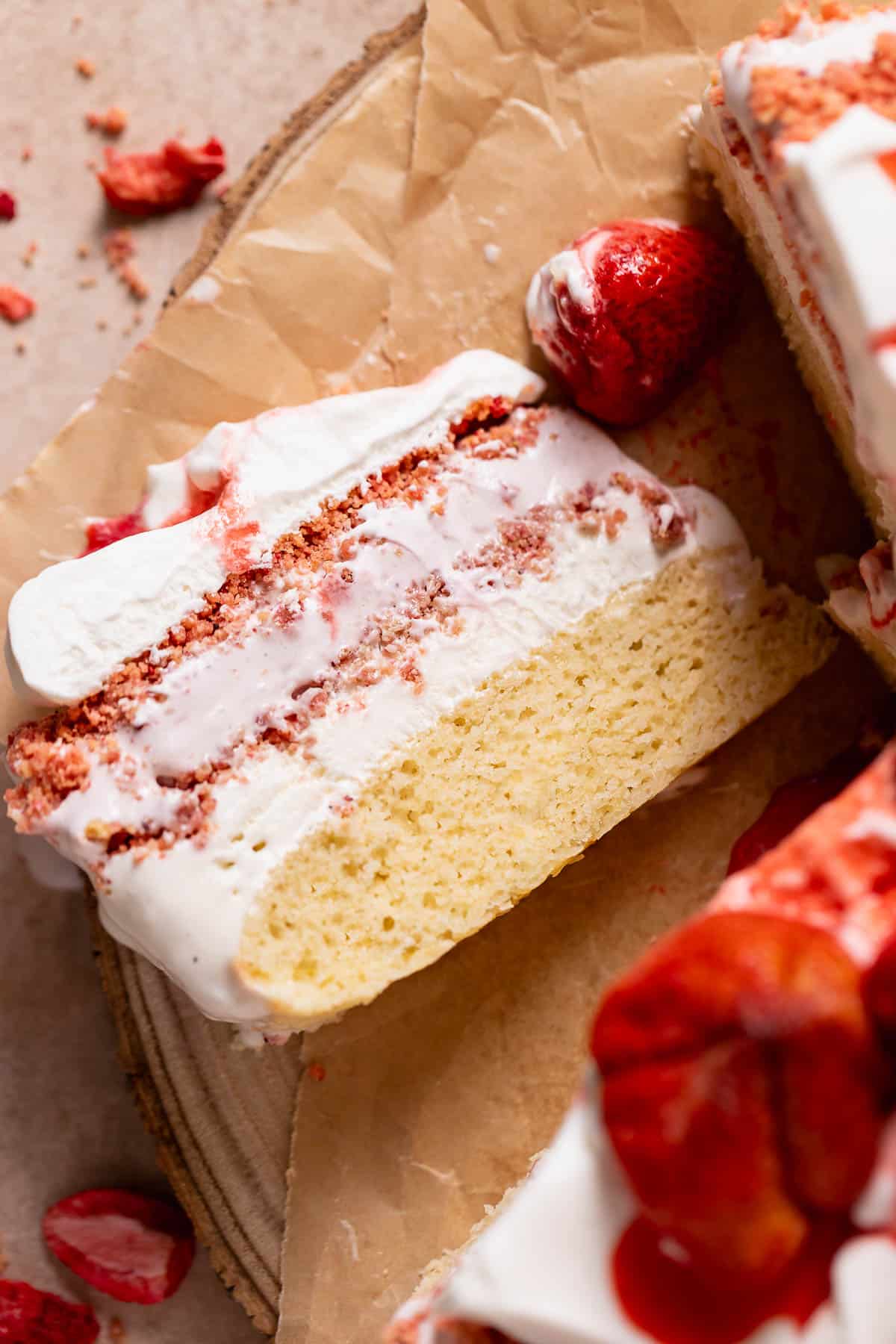 A slice of strawberry ice cream cake on a wooden platter.