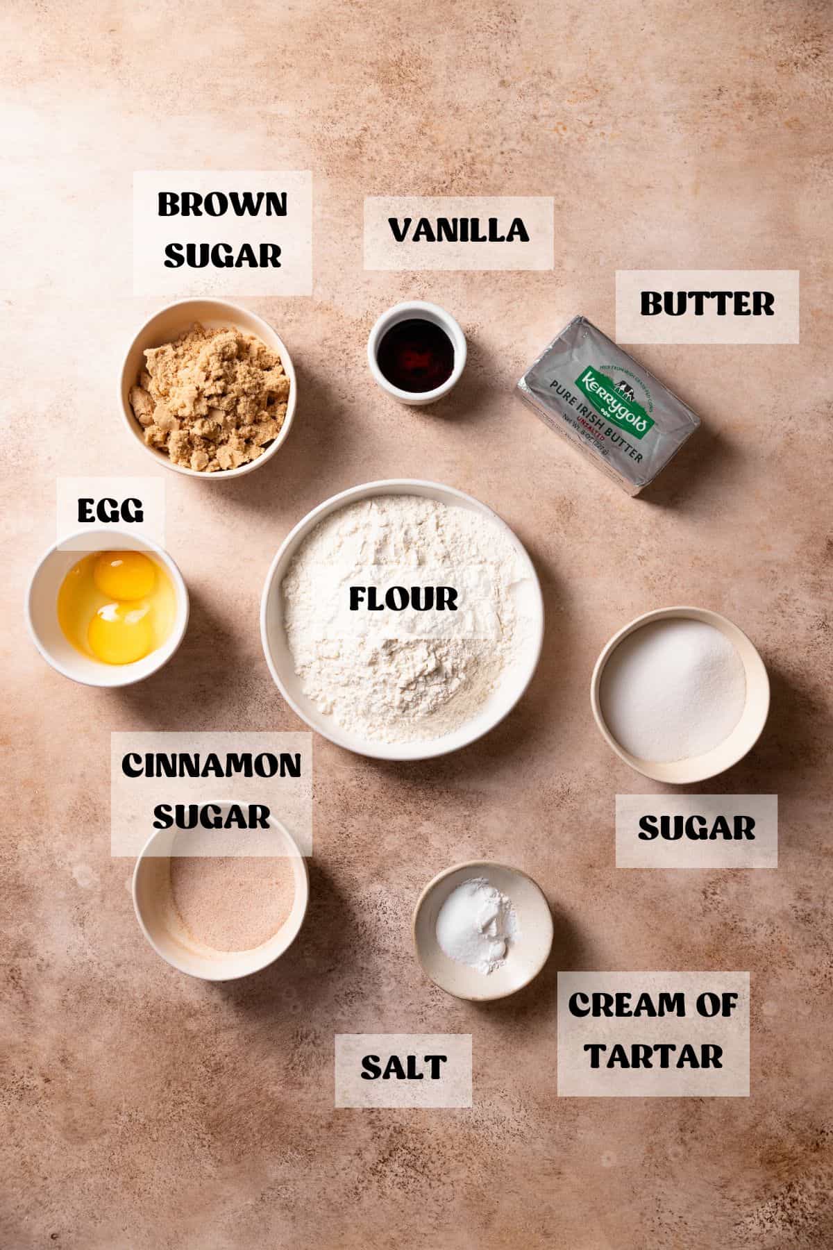 Ingredients needed to make snickerdoodle cookies in bowls with labels.