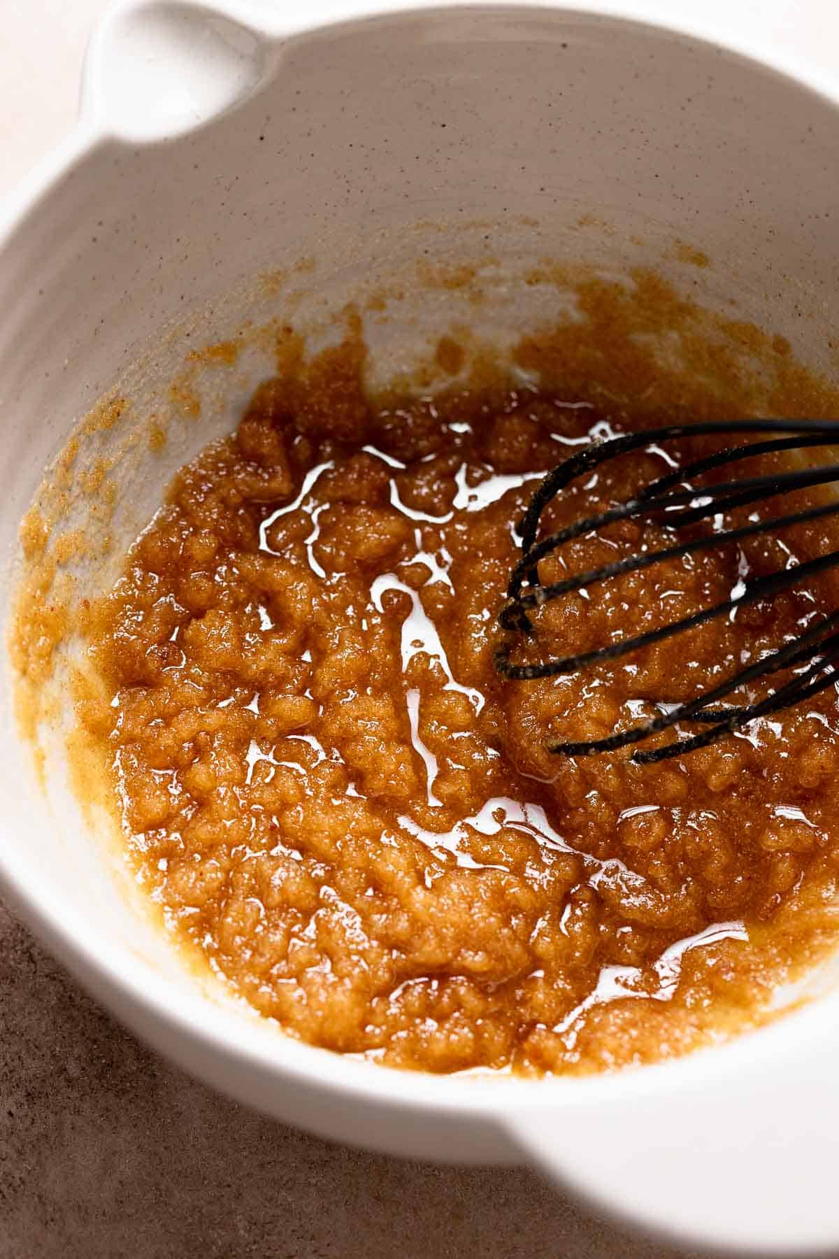 A mixing bowl with the brown butter whisked into the sugar.