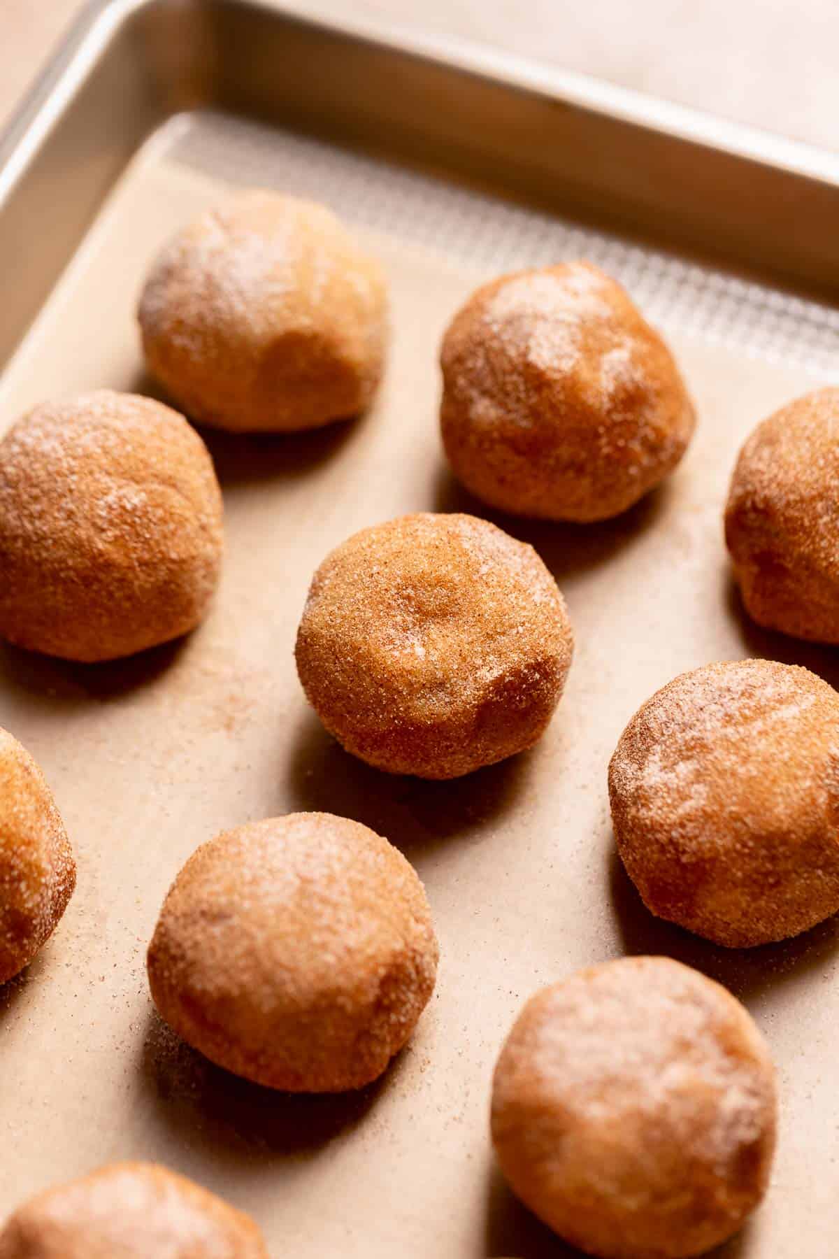 Snickerdoodle cookie dough balls on a baking sheet.