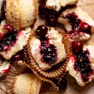 Cherry cheesecake cupcakes cut in half on brown parchment paper.