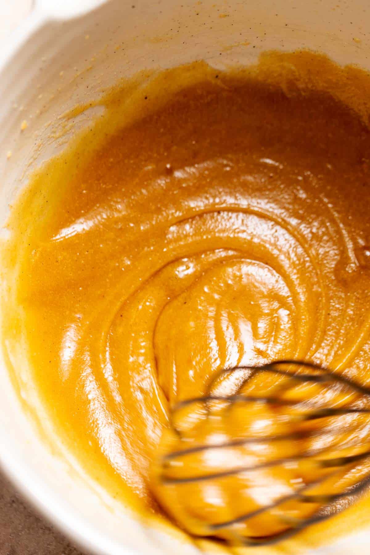 A whisk mixing together the brown butter, sugars, and eggs.