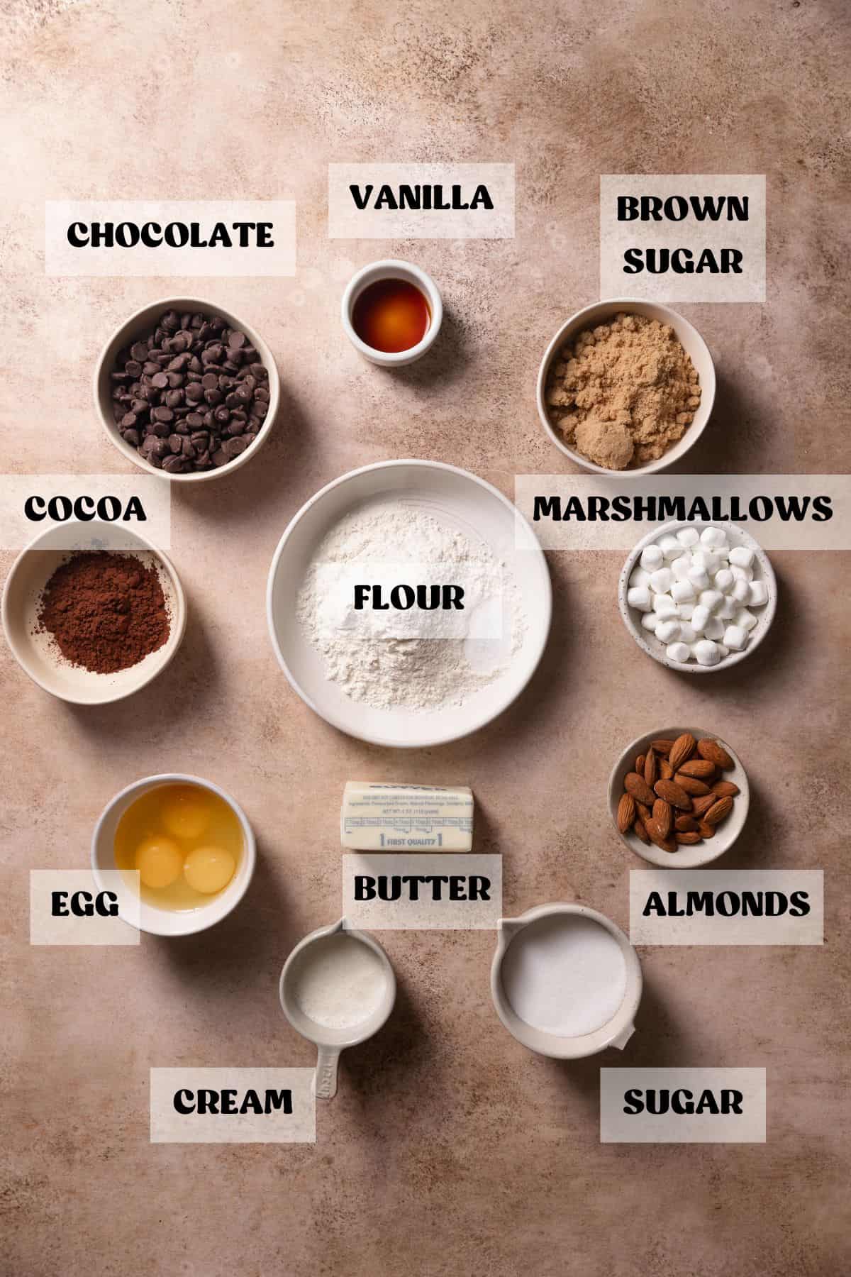Ingredients needed to make brownies with marshmallows and almonds in bowls with labels.