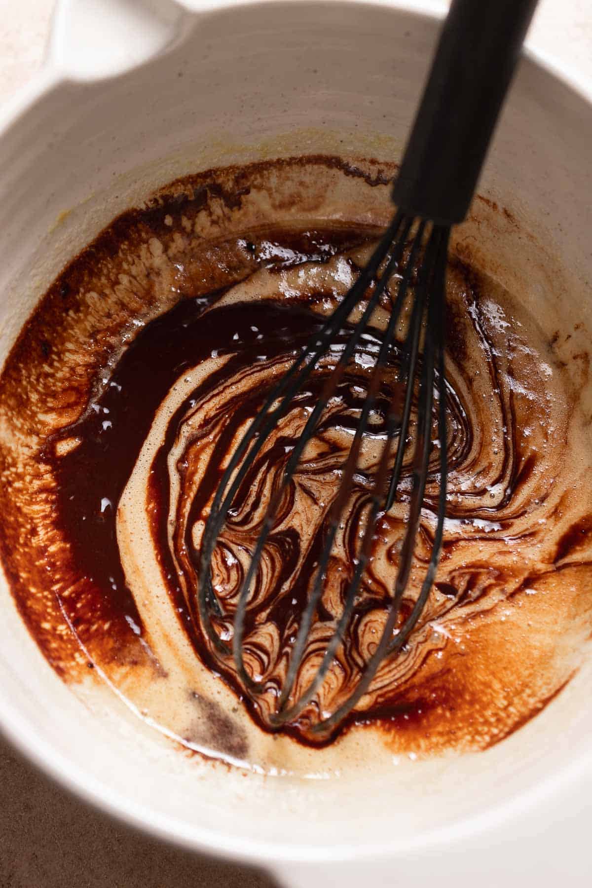 A mixing bowl with the whisked eggs and sugar with melted chocolate streamed in.