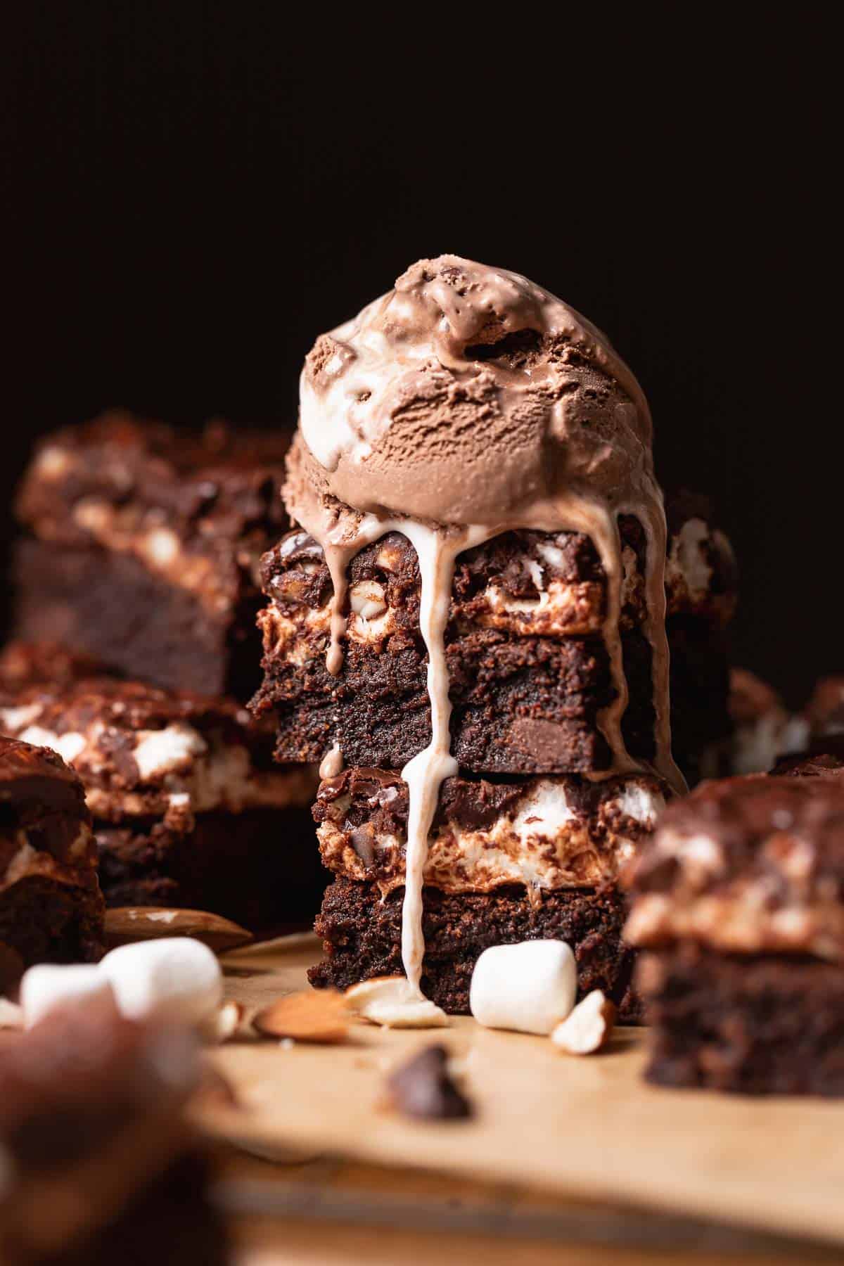 Two brownies stacked with a scoop of rocky road ice cream melting on top.