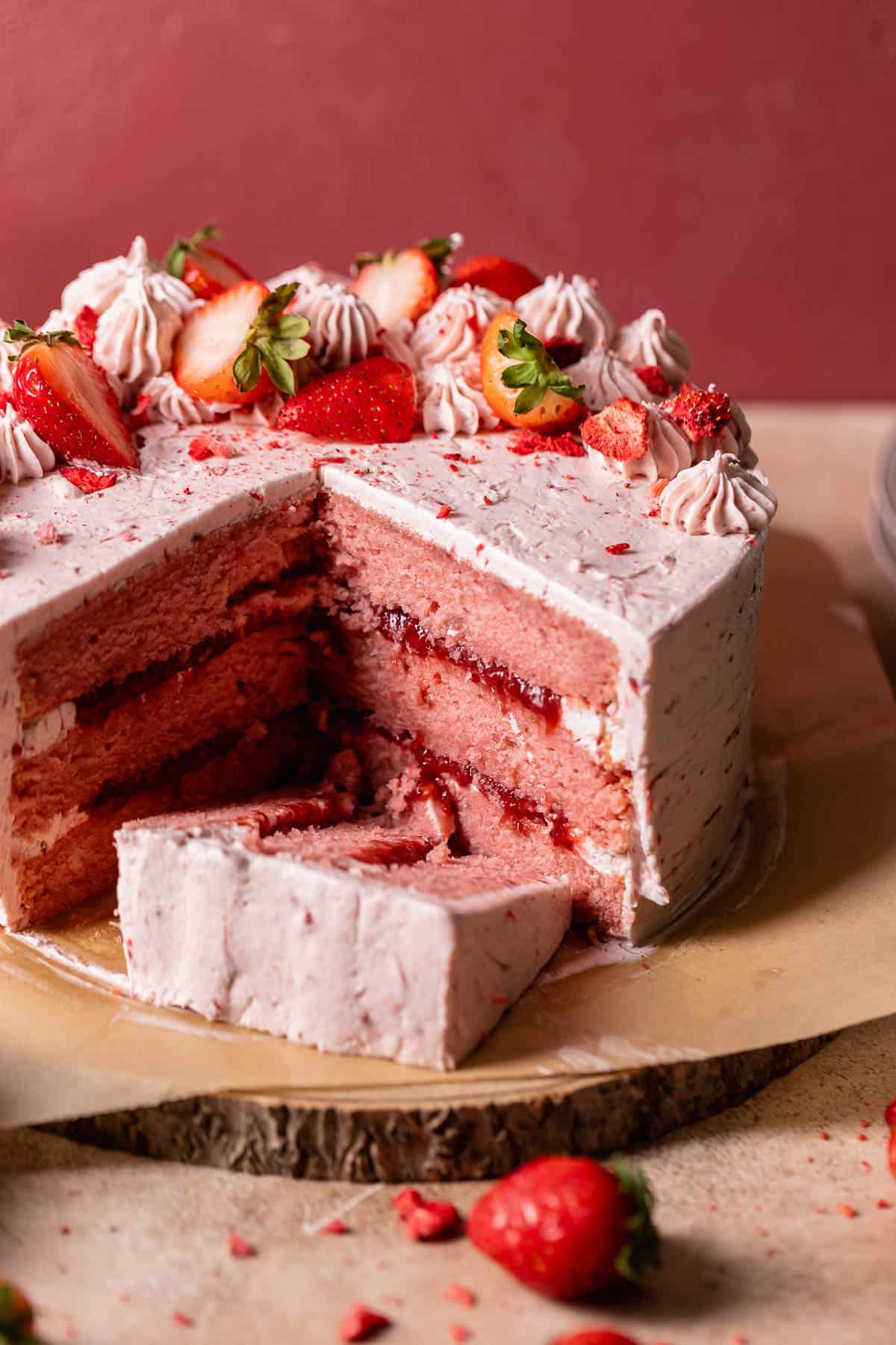 Strawberry cake with fresh strawberries on a wooden cake board.