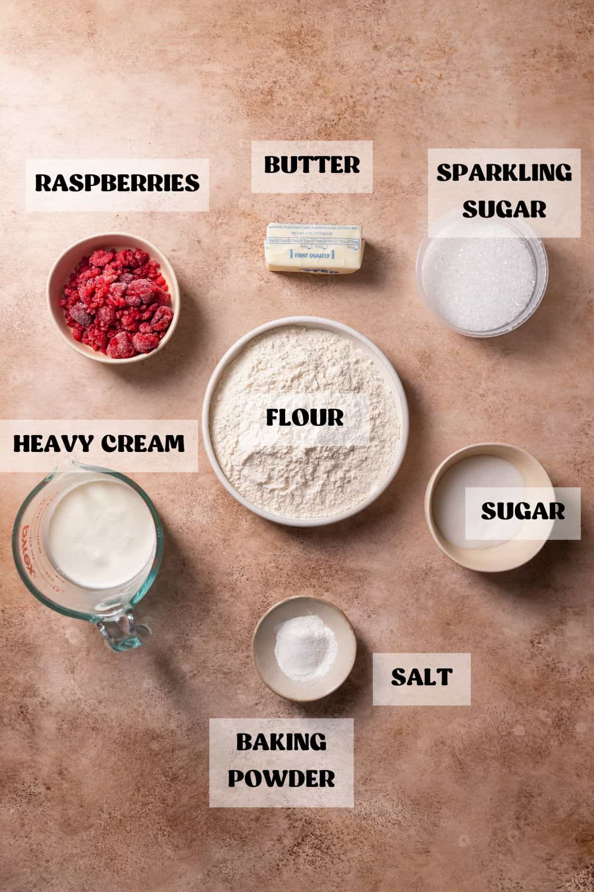 Ingredients needed to make raspberry cream scones in bowls with labels.