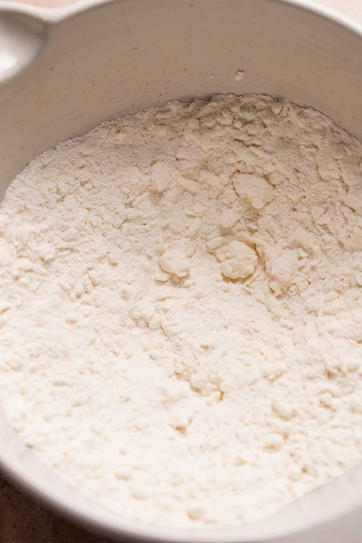 A large bowl with the dry ingredients and pea-sized butter for the scones.