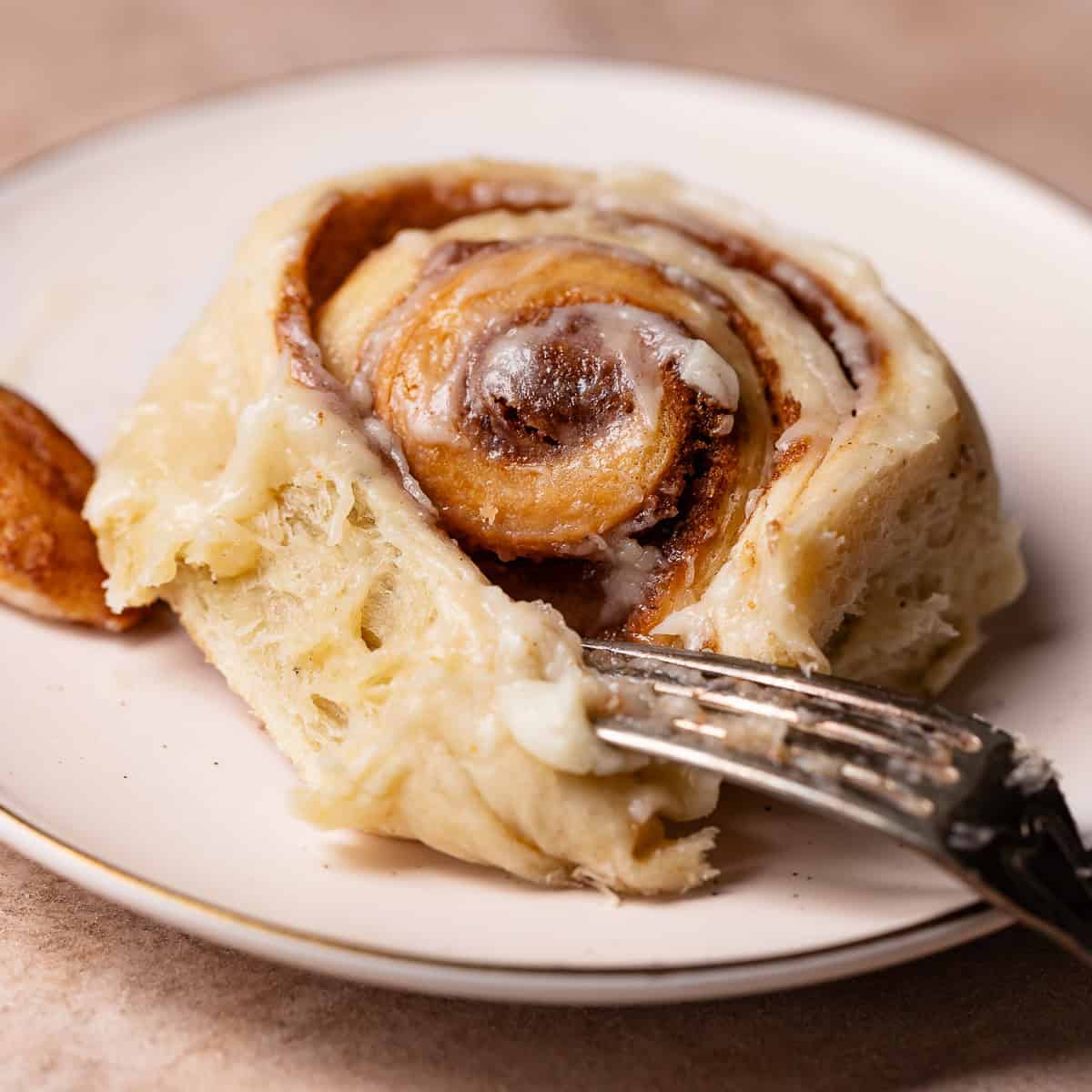 Brown butter rolls on a white plate with a fork digging into it.