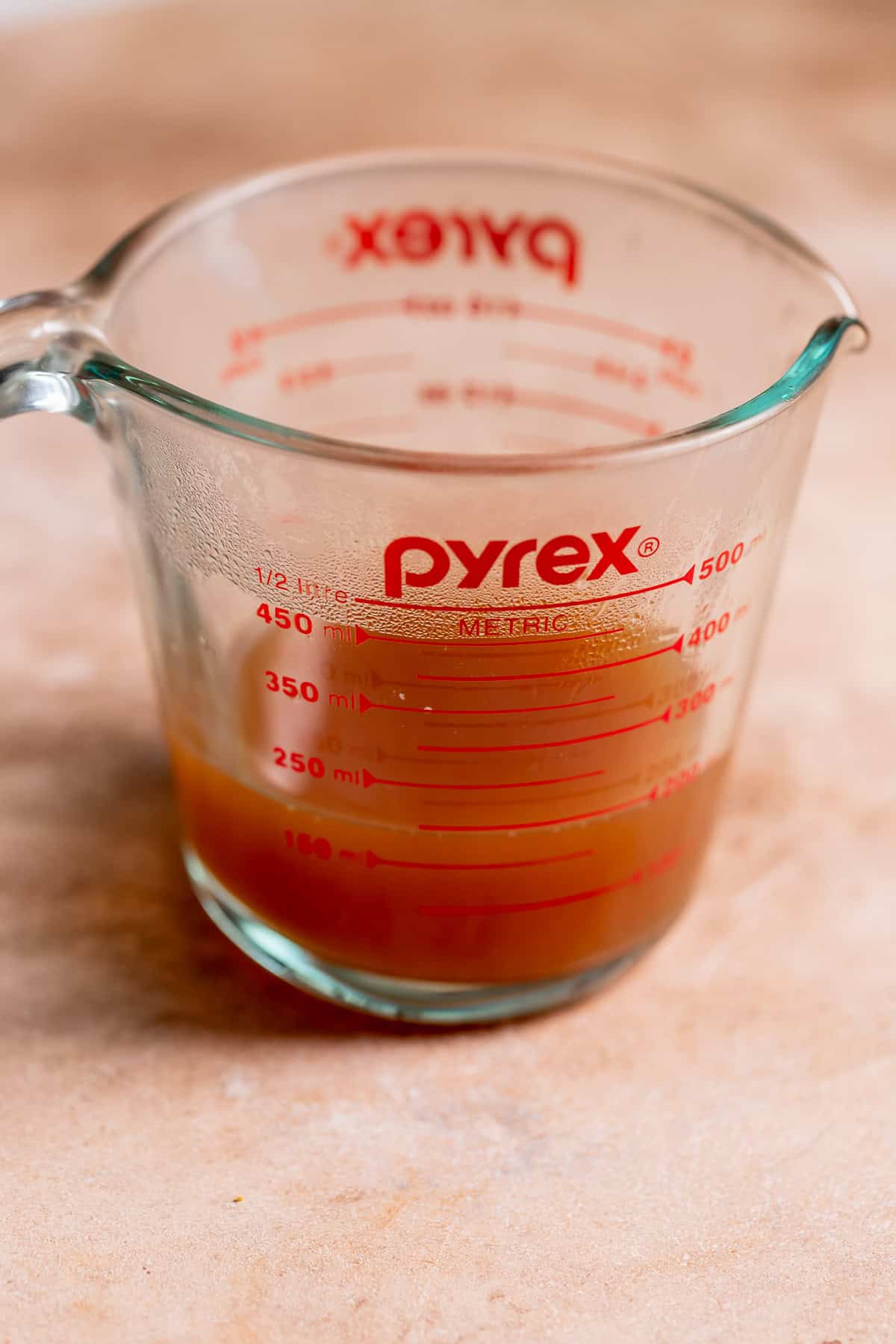 A glass measuring cup with reduced apple cider.