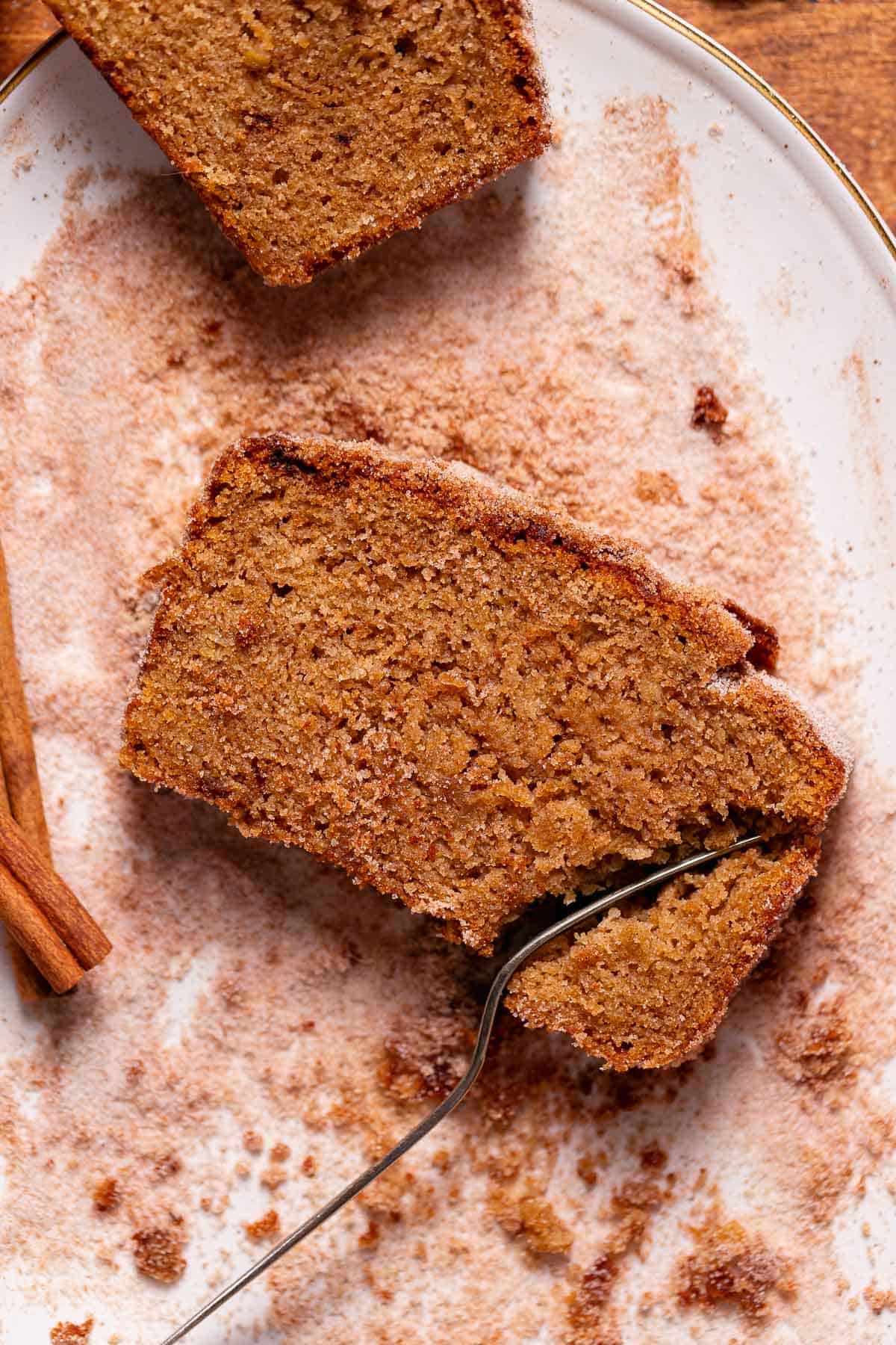 A slice of apple cider loaf being cut into with a fork.