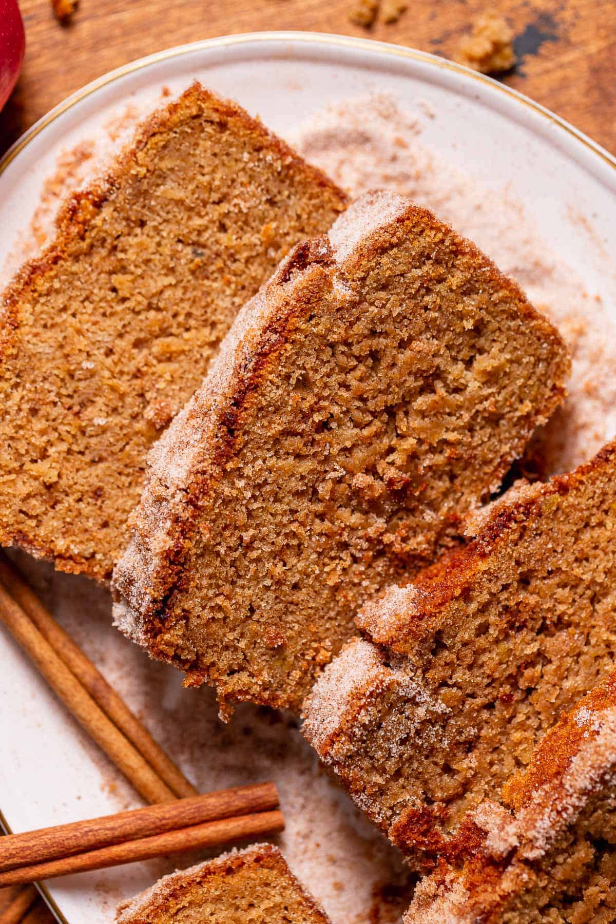 Slices of apple cider cake on a white plate surrounded by cinnamon sugar.