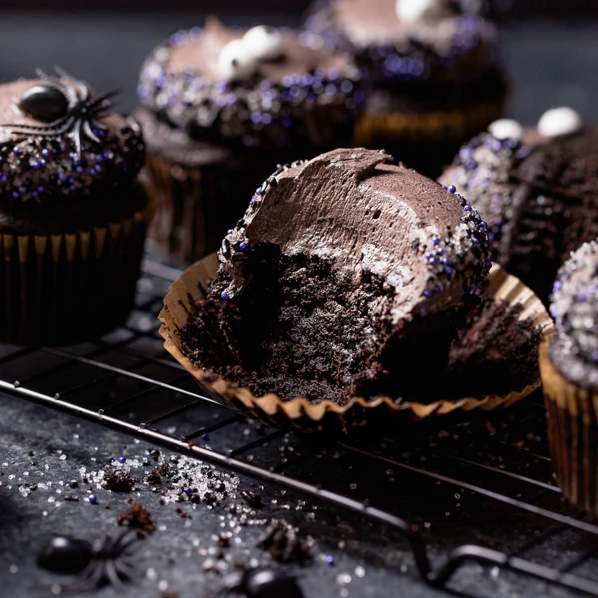 Black velvet cupcake with a bite missing on a wire rack.