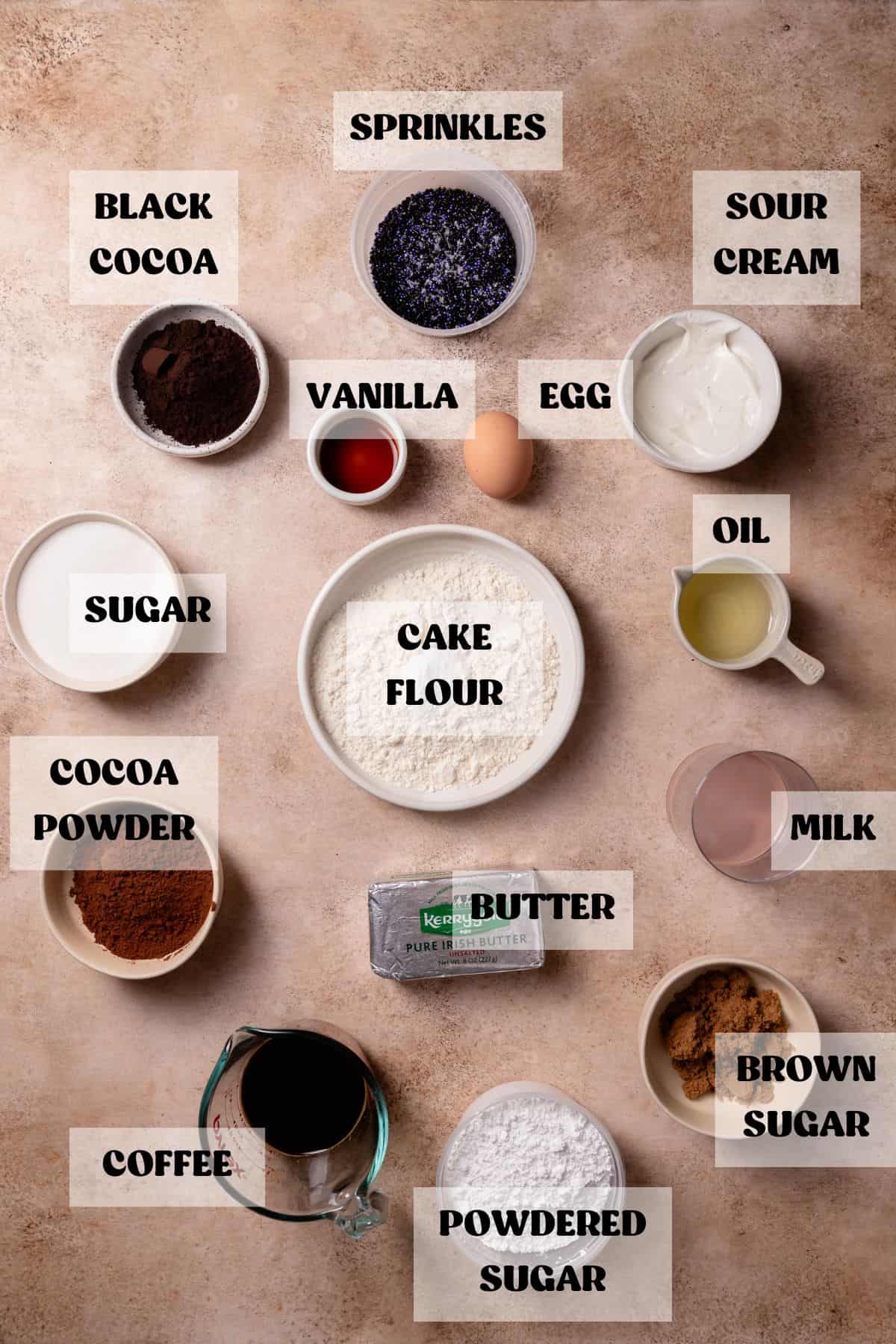 Ingredients needed to make black cocoa cupcakes in bowls with labels.