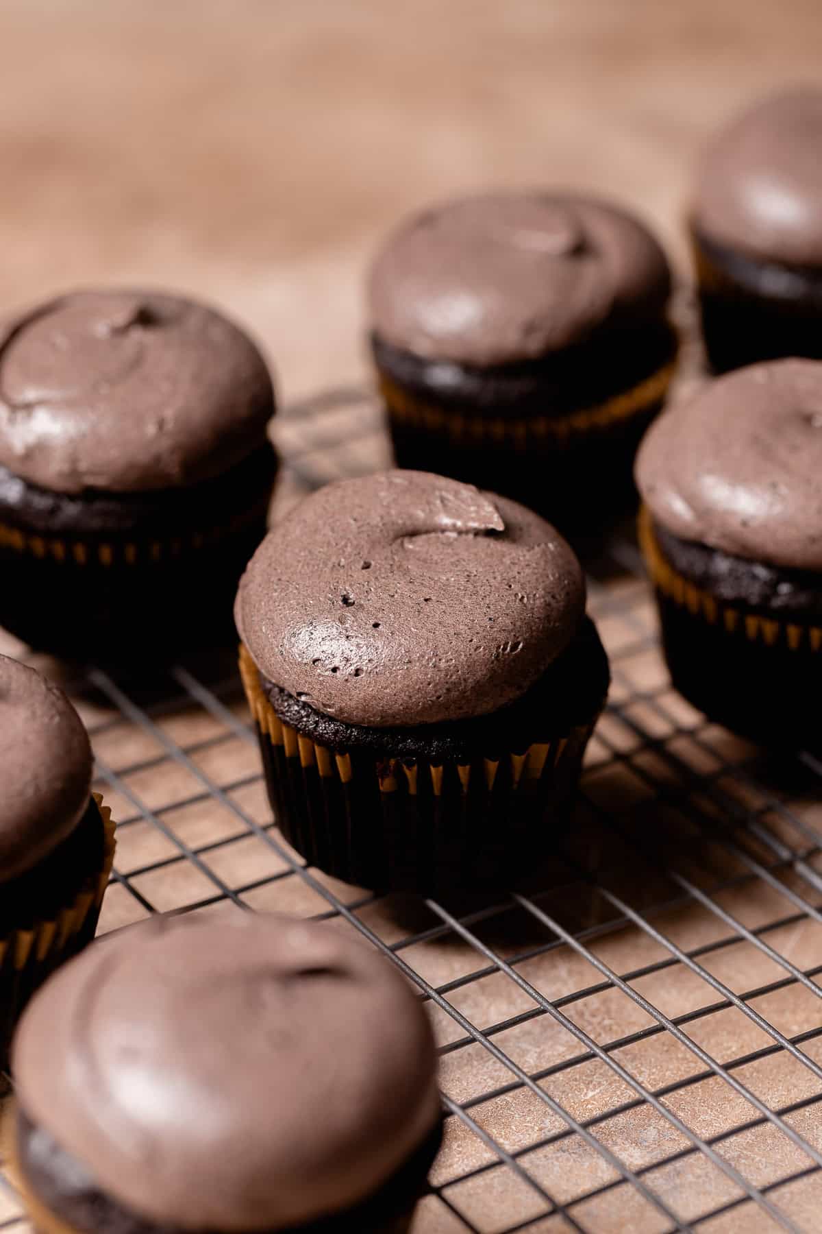 Black cupcakes on a wire rack with black buttercream on top.