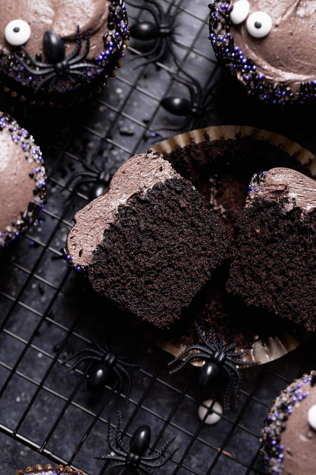 A black chocolate cupcake cut in half on a wire rack.