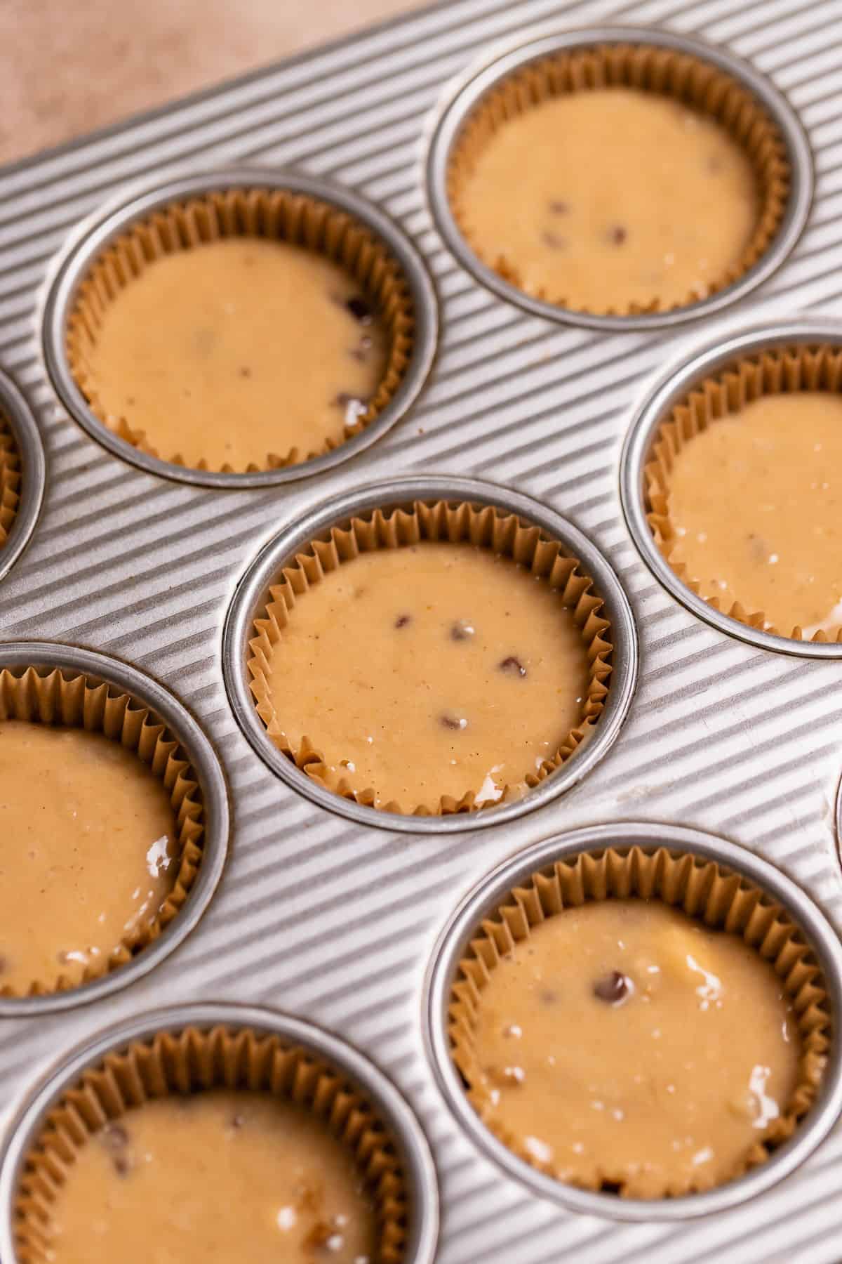 A cupcake pan with liners full of cupcake batter before baking.