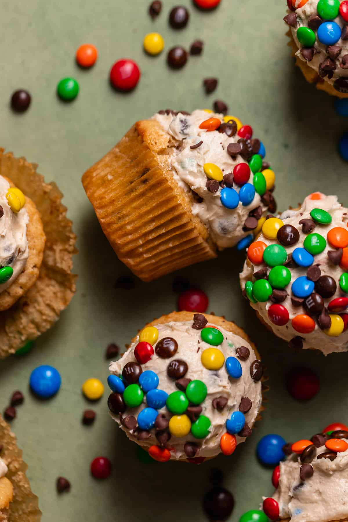 Monster cookie dough cupcakes on a green backdrop.