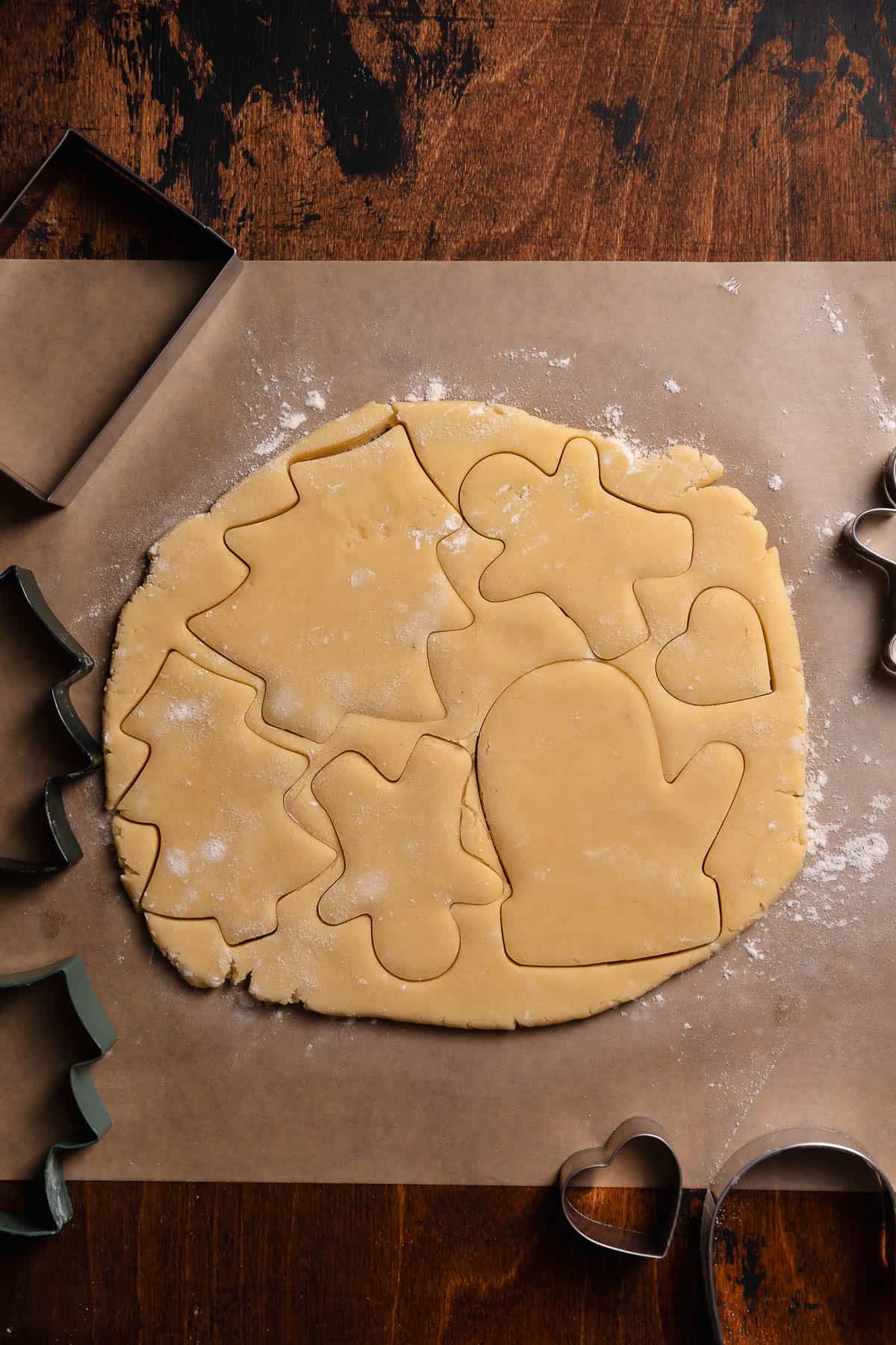 A slab of rolled out cookie dough with cookie cutter imprints.