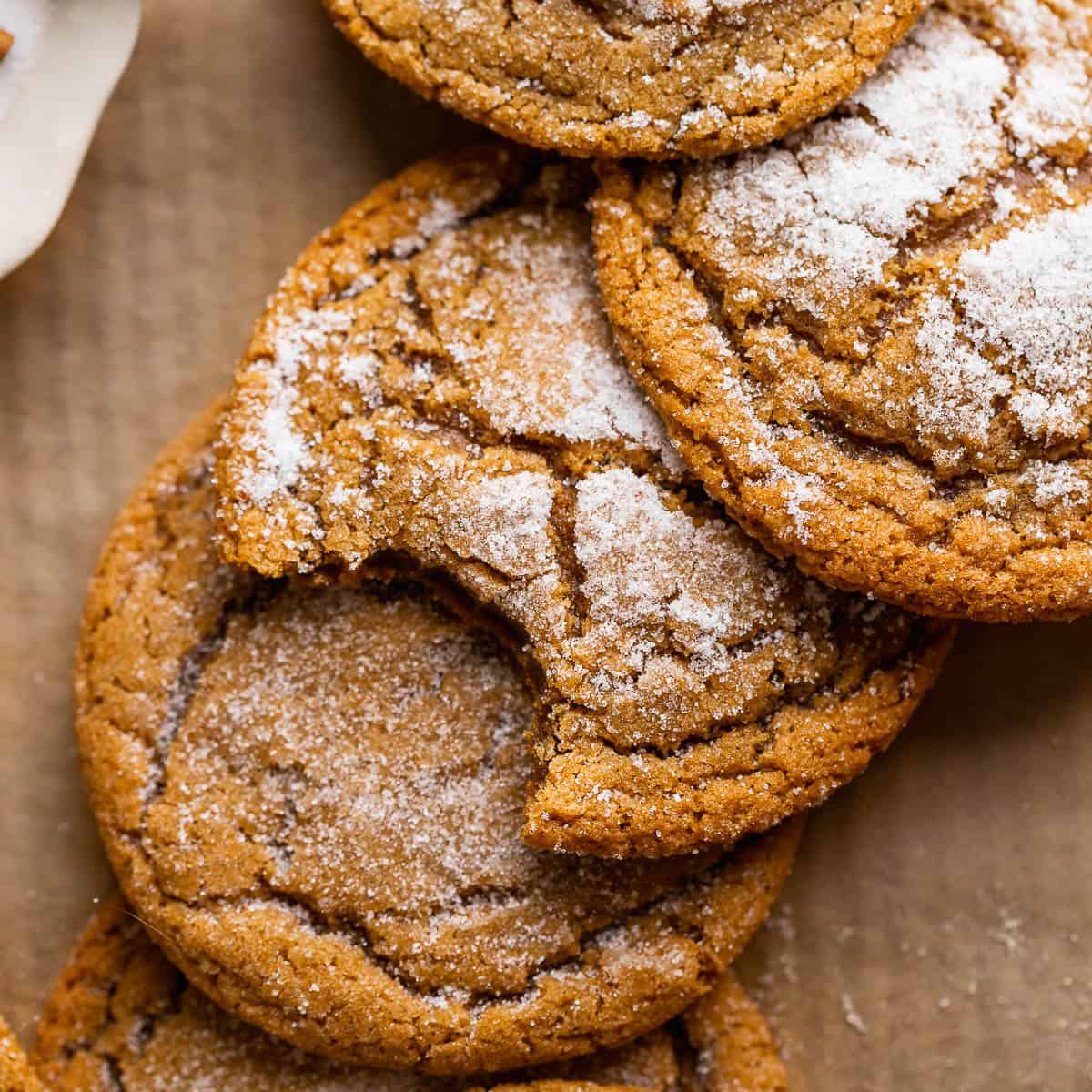 Molasses cookies with crinkle tops on brown parchment paper.