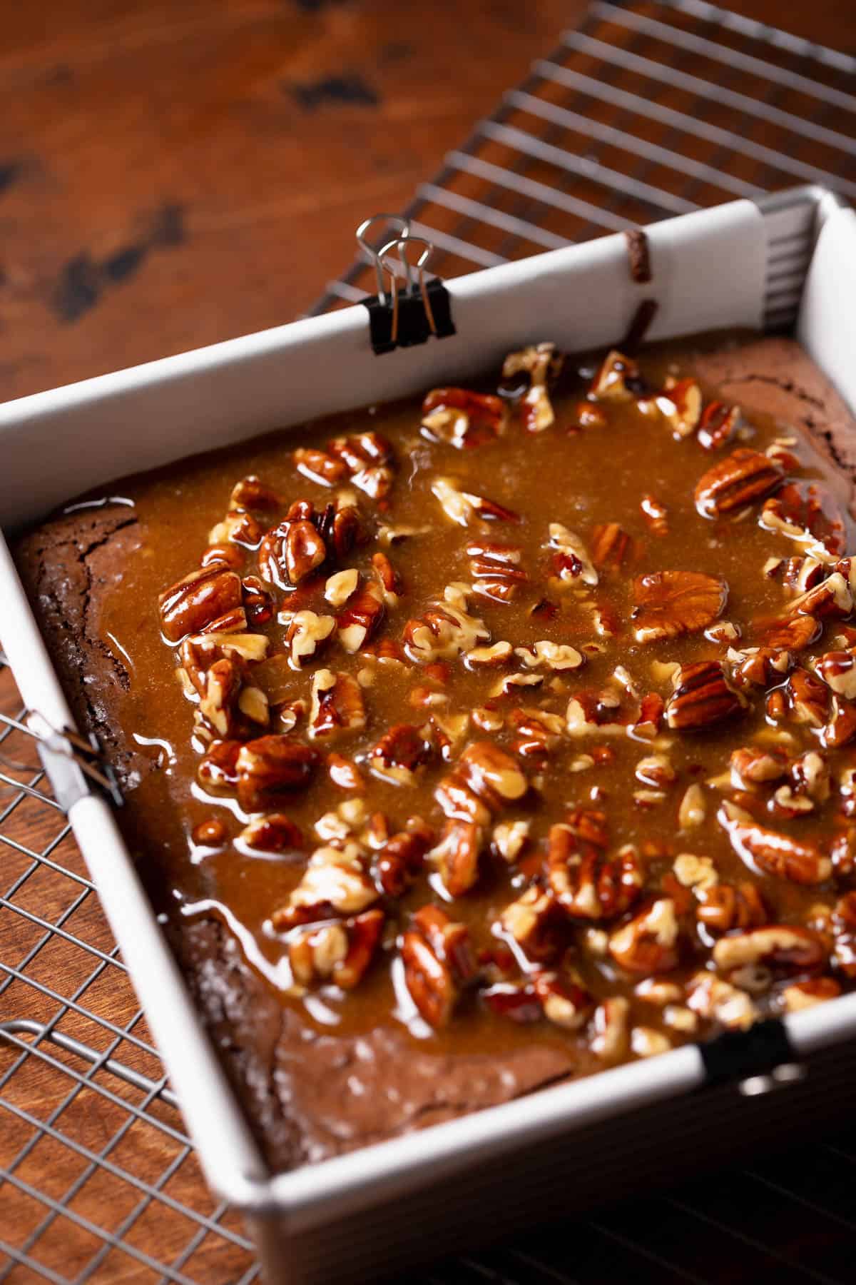 The pecan filling being poured over the top of the baked brownie.