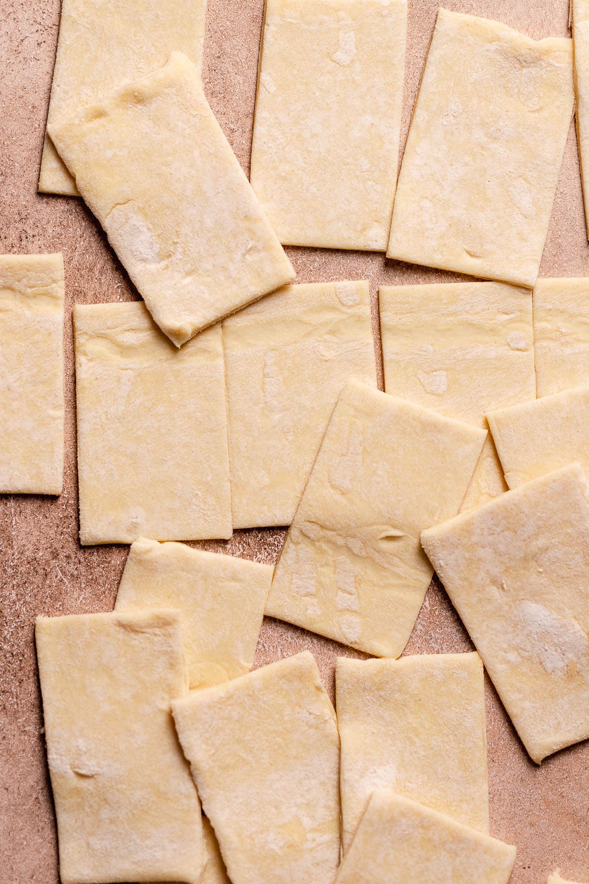 Squares of puff pastry on a wooden surface.