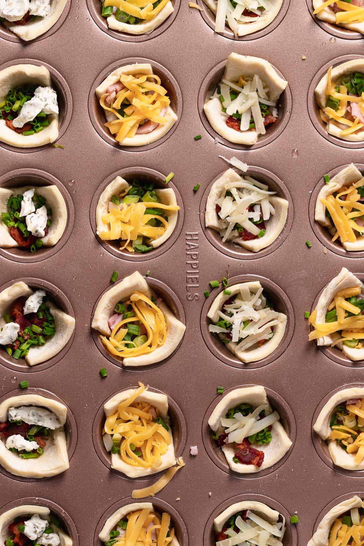 An overhead shot of the muffin pan filled with puff pastry and various fillings.