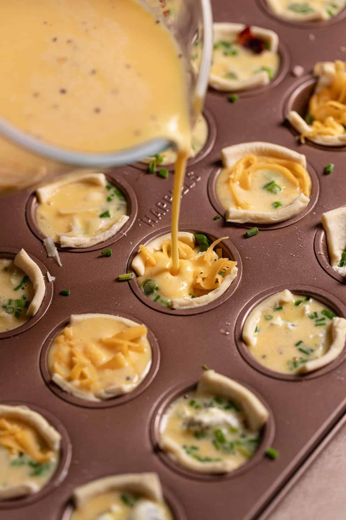 Egg filling being poured into each puff pastry cup.