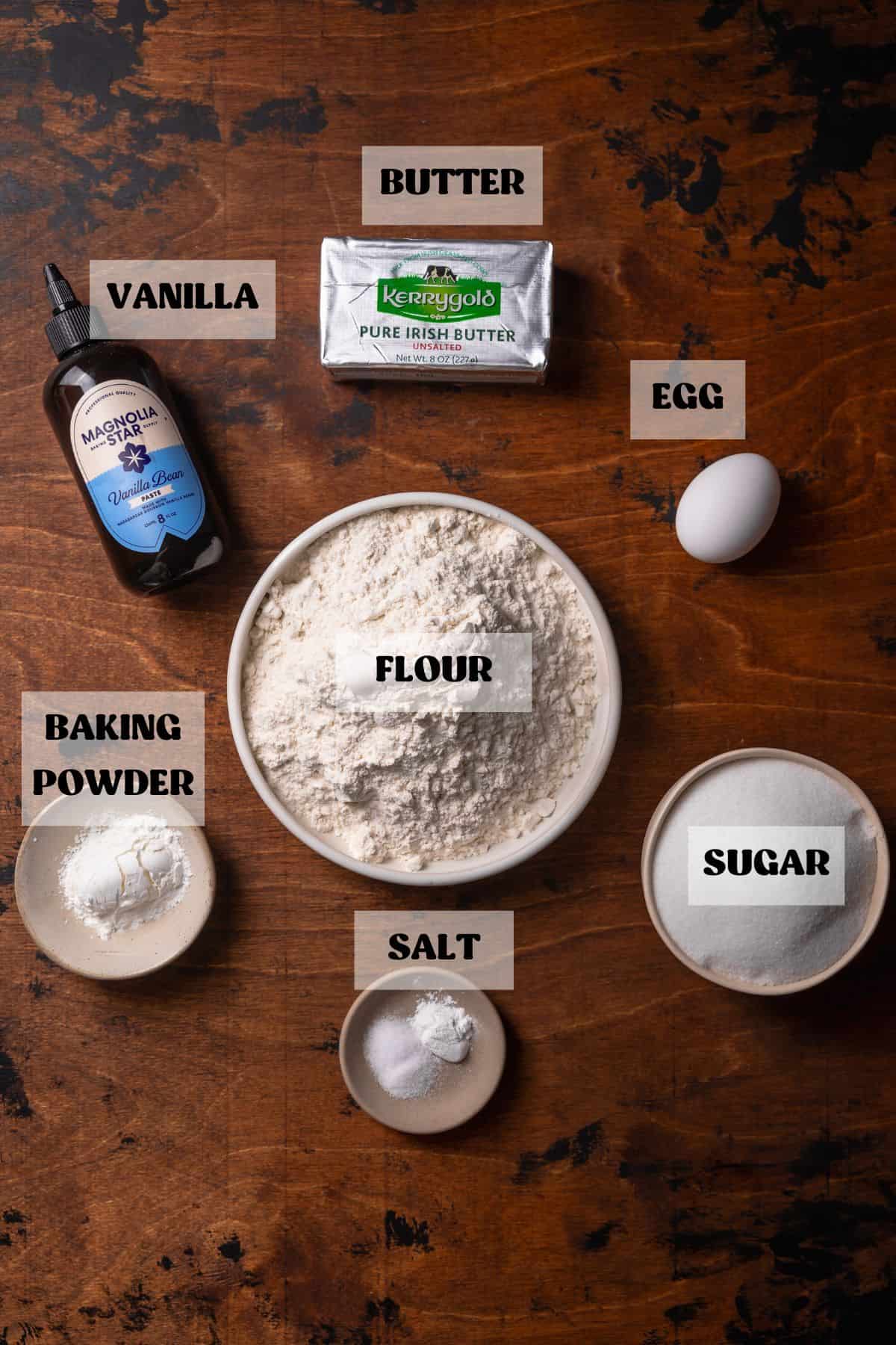 Ingredients needed to make classic sugar cookies in bowls with labels.