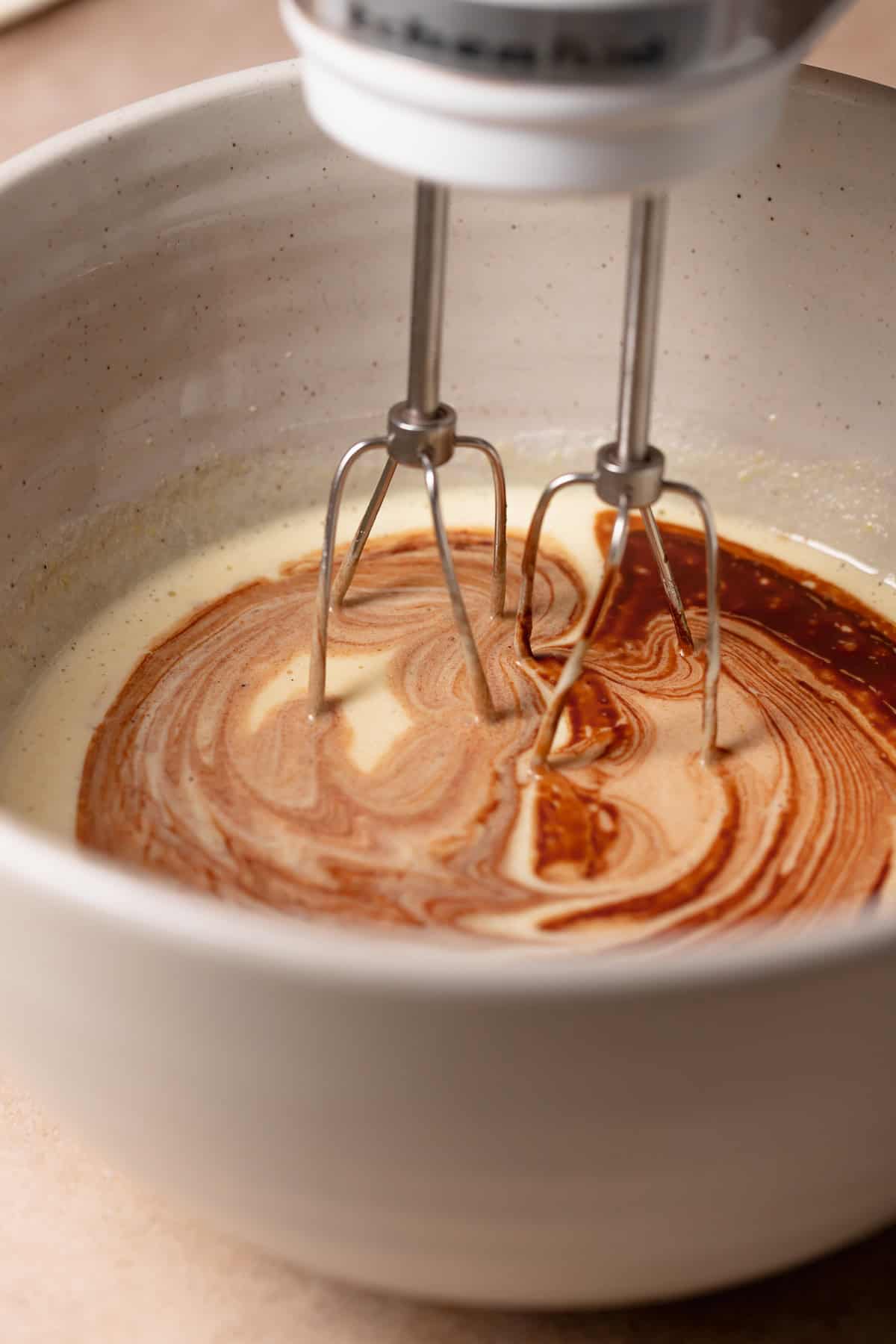 The melted chocolate being mixed into the beaten eggs and sugar.