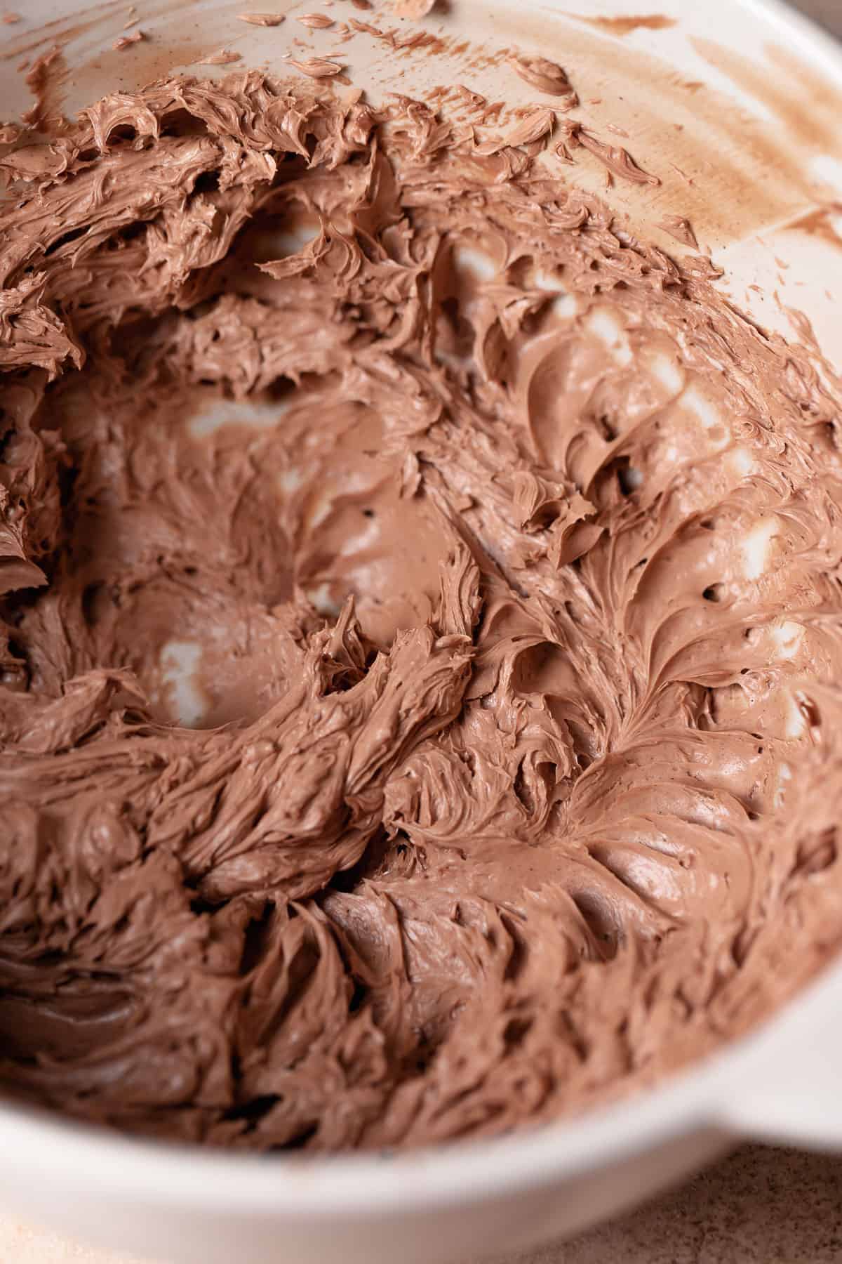 A mixing bowl with milk chocolate buttercream in it.